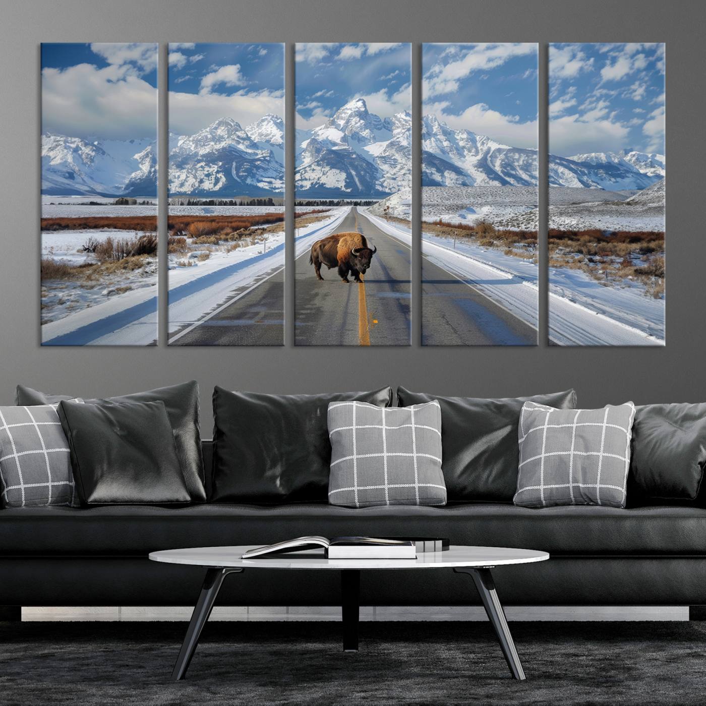 A powerful bison stands on a snow-dusted road beneath the towering peaks of the Grand Tetons, capturing the untamed beauty of America's winter wilderness.