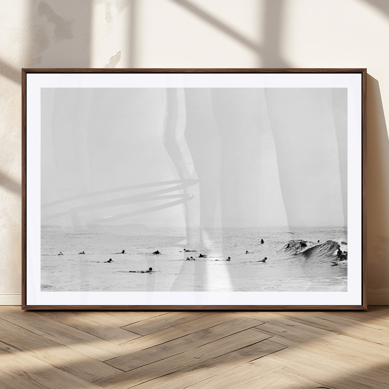 A group of surfers floating in the ocean, waiting for waves under a vast, moody sky, captured in black and white.