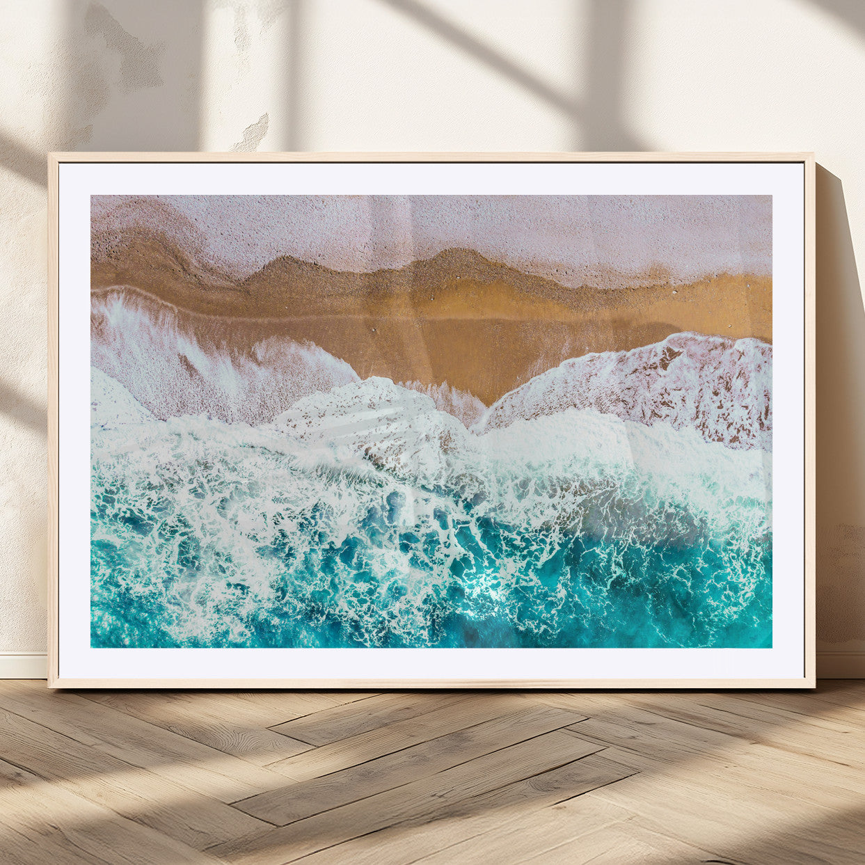 Aerial view of ocean waves crashing onto a sandy beach, with turquoise water and foamy white surf, creating a serene coastal aesthetic for home decor.