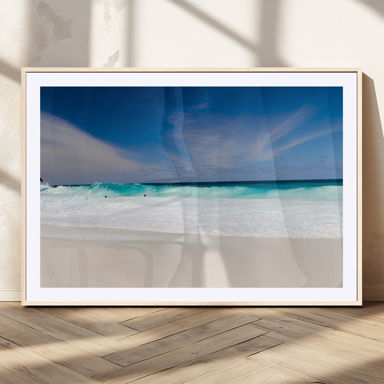 Turquoise waves crash onto a pristine white sand beach under a vivid blue sky with wispy clouds, creating a peaceful and refreshing coastal scene.
