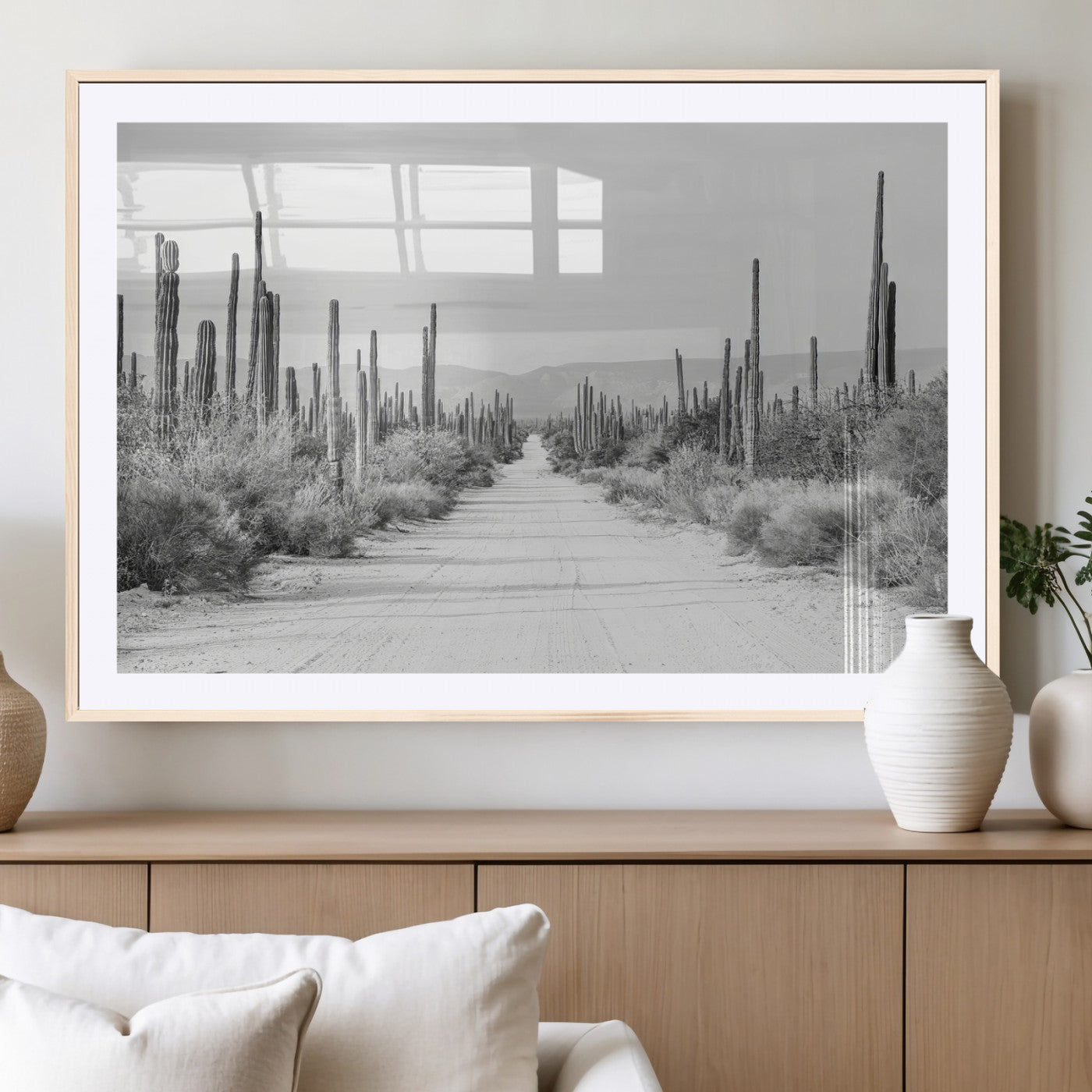 A black and white desert road stretching through a cactus-filled landscape, creating a rugged and timeless southwestern aesthetic with a sense of adventure.