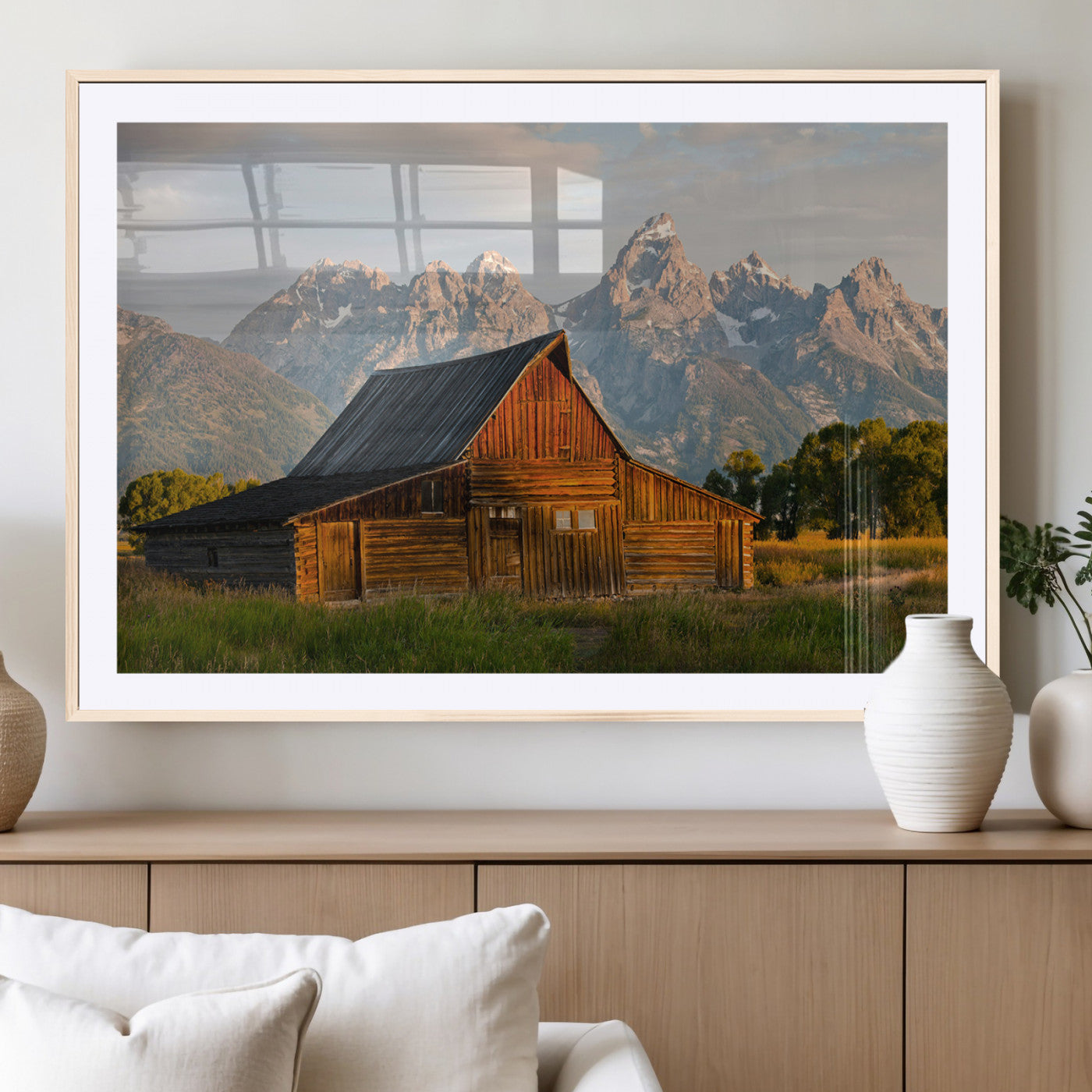 Rustic wooden barn set against towering mountain peaks under warm golden light, creating a peaceful Western countryside scene.