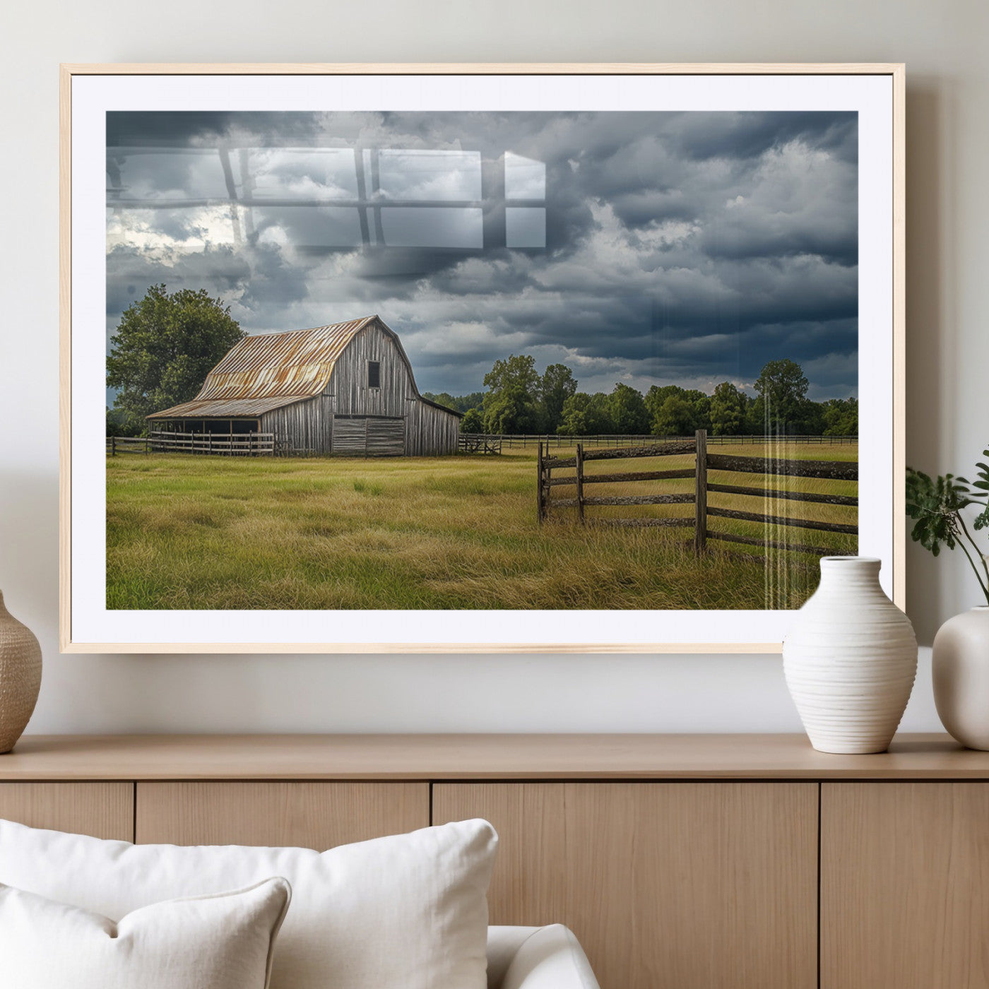"Rustic barn in a wide open field under a dramatic sky with dark clouds, surrounded by a wooden fence and lush green trees."