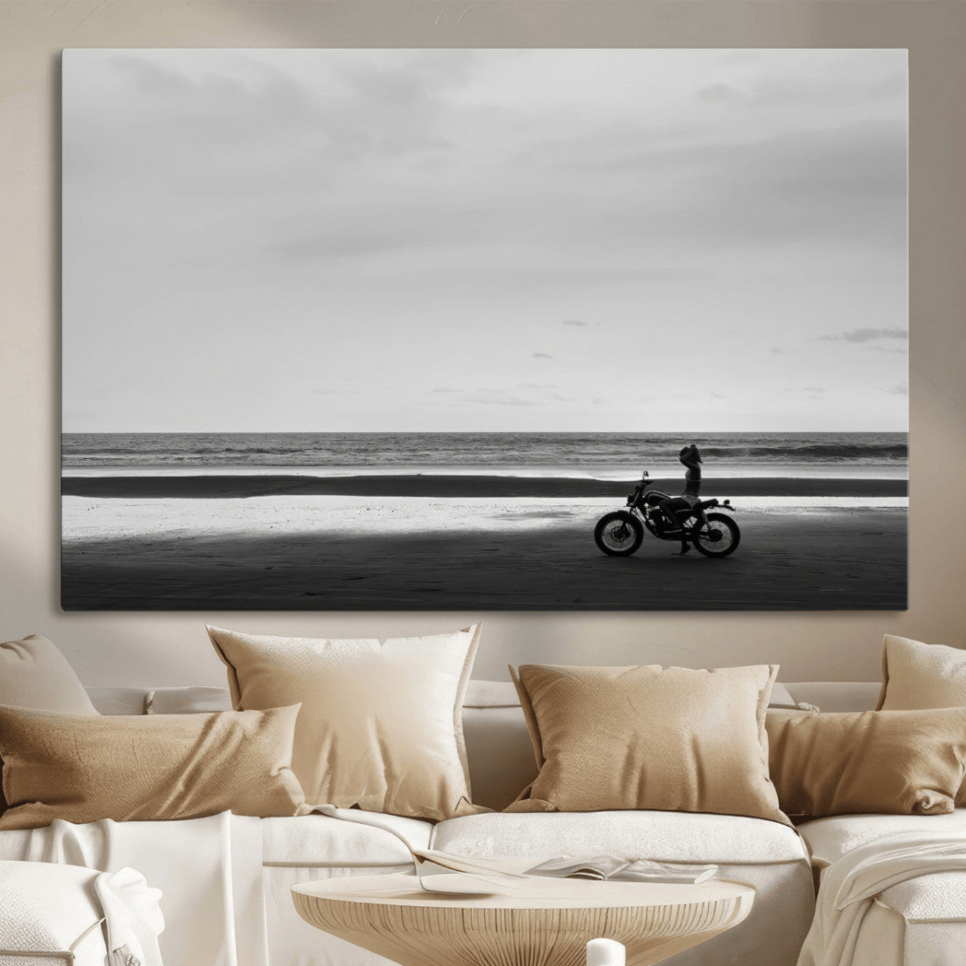 A motorcyclist on a vast beach, gazing at the ocean, capturing a moody and tranquil coastal adventure in black and white.