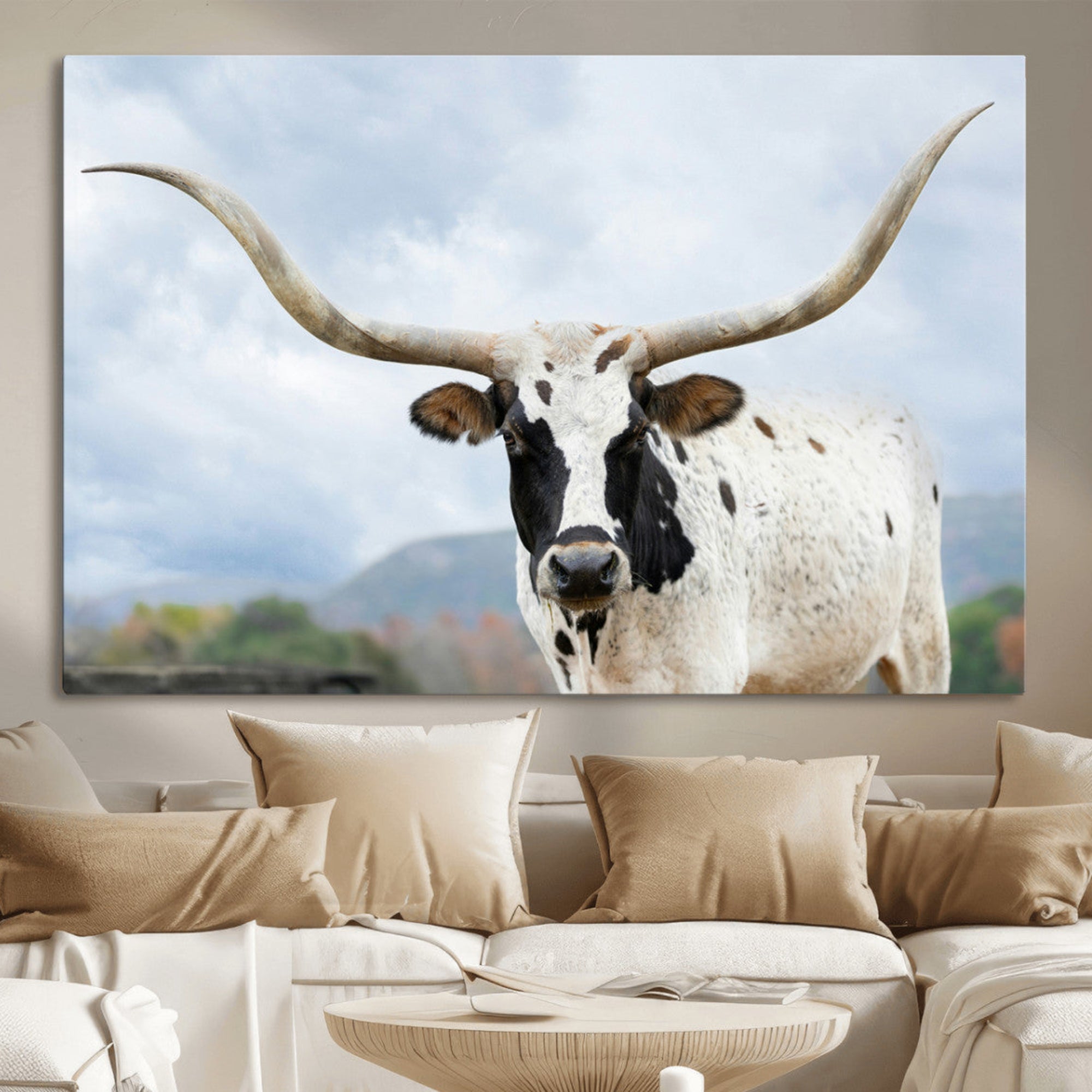 Close-up of a Texas Longhorn with curved horns, black and white markings, set against a cloudy sky and distant hills, perfect for rustic decor.