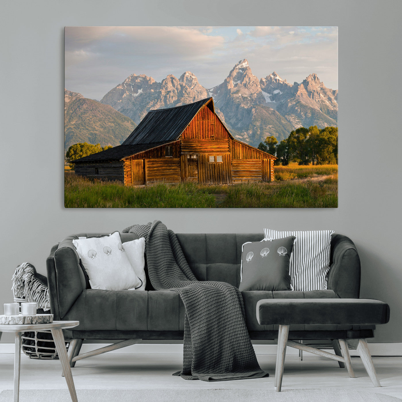 Rustic wooden barn set against towering mountain peaks under warm golden light, creating a peaceful Western countryside scene.