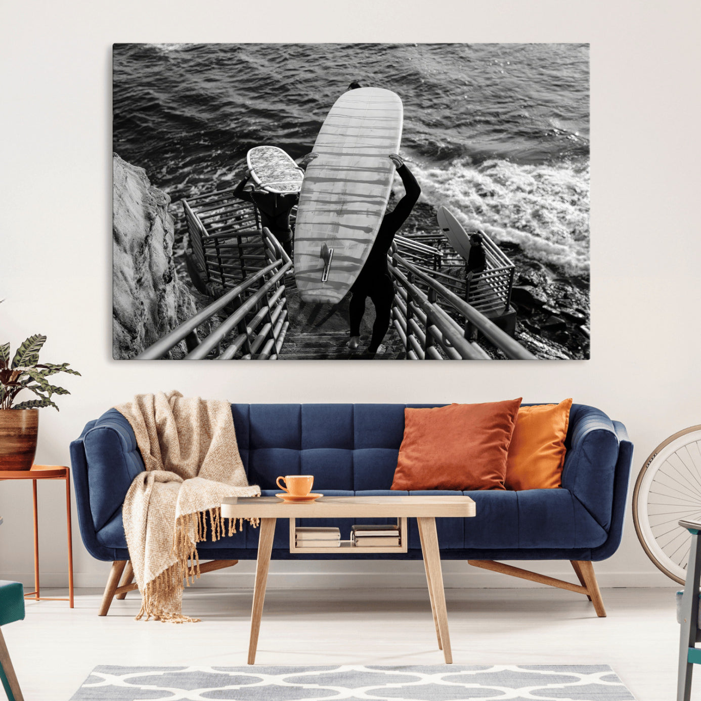 Black and white photo of surfers carrying boards down a rugged cliffside stairway, capturing a bold and adventurous coastal scene.