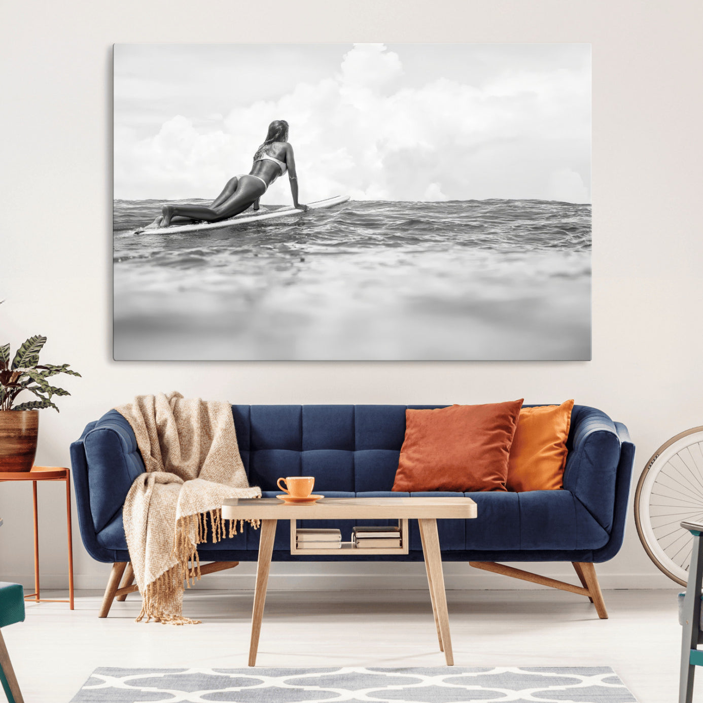A black and white ocean scene featuring a surfer girl waiting on her board, gazing at the horizon, capturing a tranquil and adventurous coastal moment.