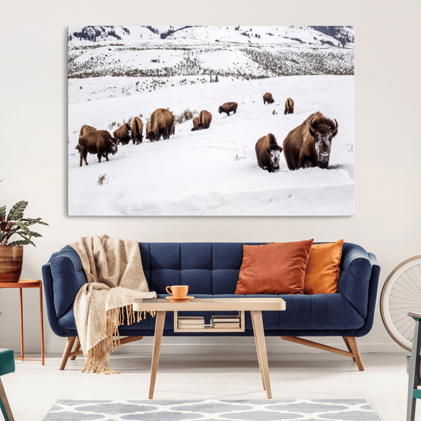 A herd of bison walking through deep snow in a mountain valley, perfect for rustic, cabin or western-themed wall decor.