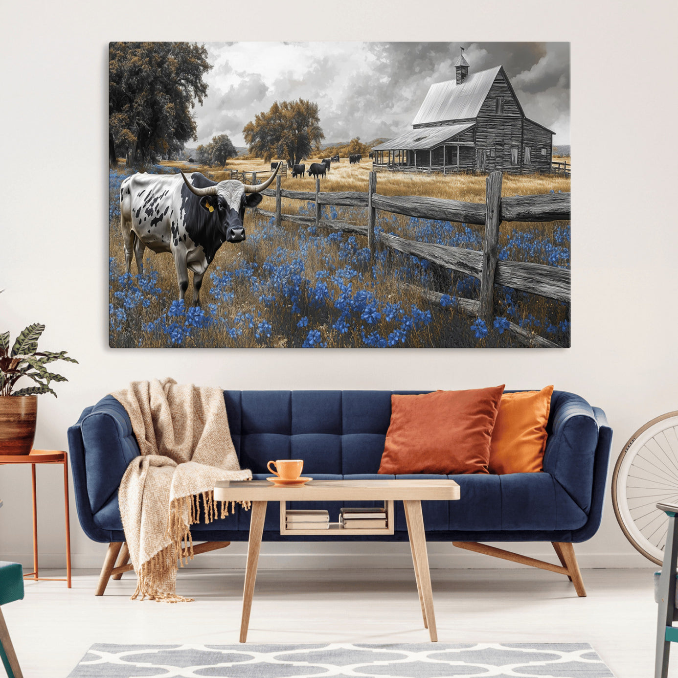 A Texas longhorn stands in front of a rustic barn and wooden fence, with bluebonnets and grazing cattle under dramatic skies.