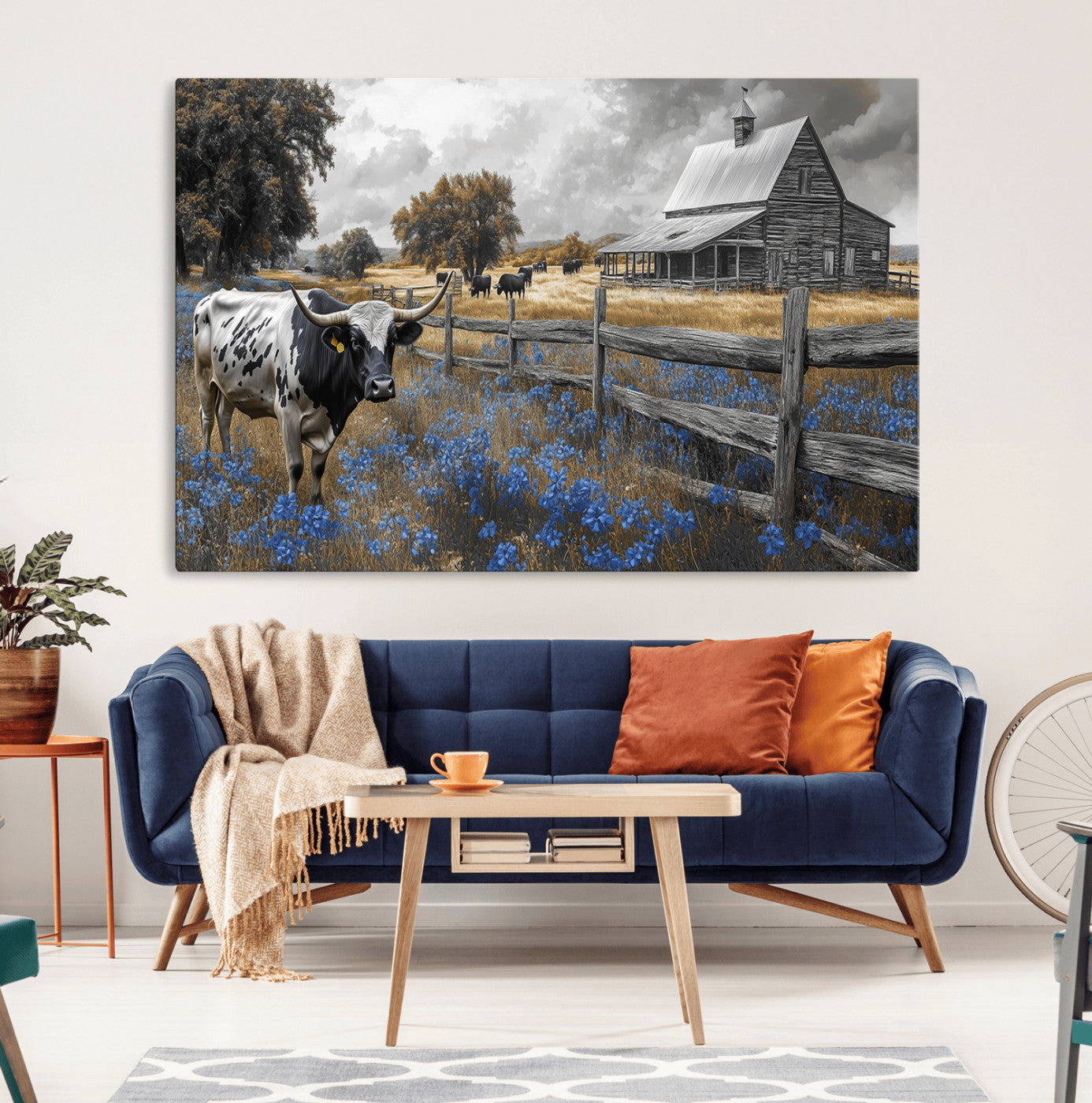 A Texas longhorn stands in front of a rustic barn and wooden fence, with bluebonnets and grazing cattle under dramatic skies.