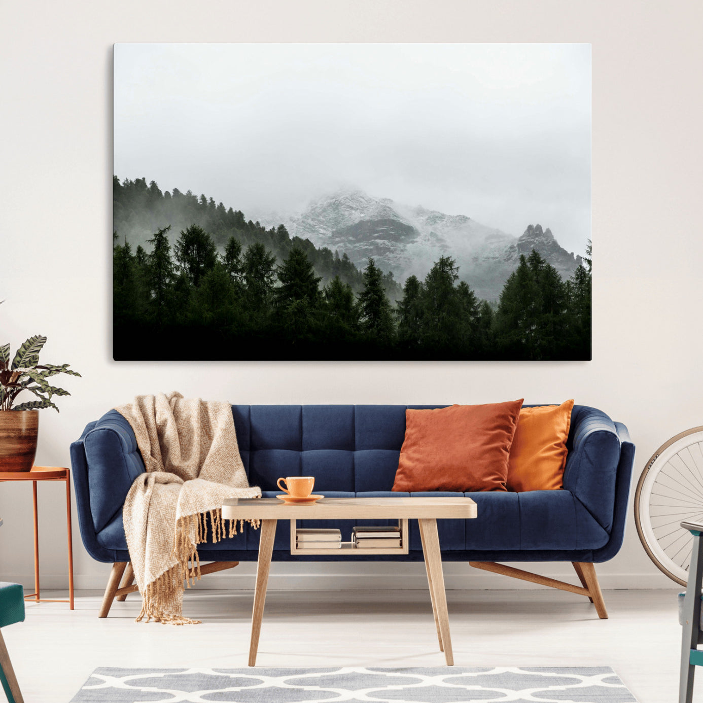 Snow-covered mountains emerging from a misty evergreen forest, creating a tranquil and moody wilderness landscape.