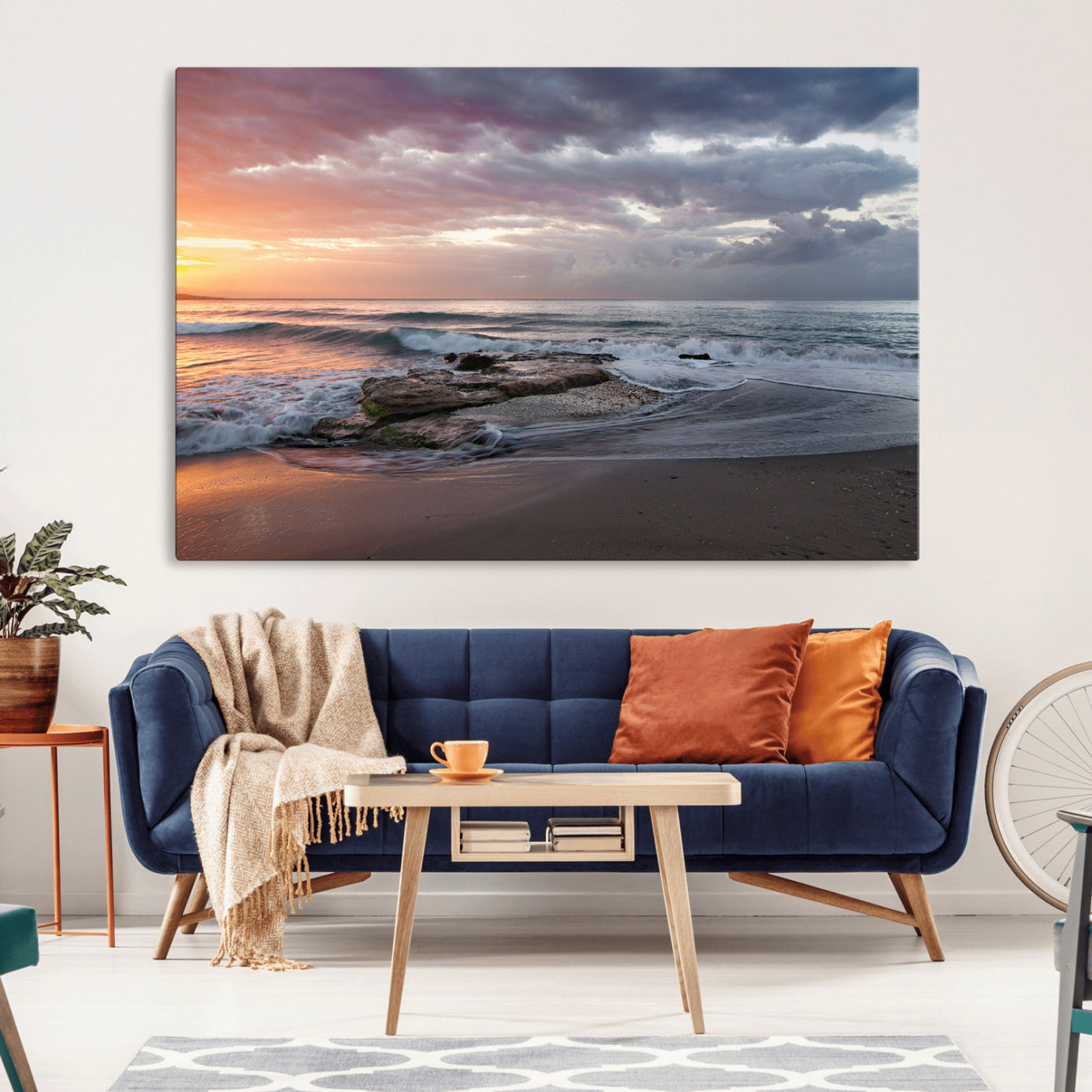 Dramatic sunset over a rocky shoreline with ocean waves gently reaching the sandy beach, creating a serene and coastal atmosphere.