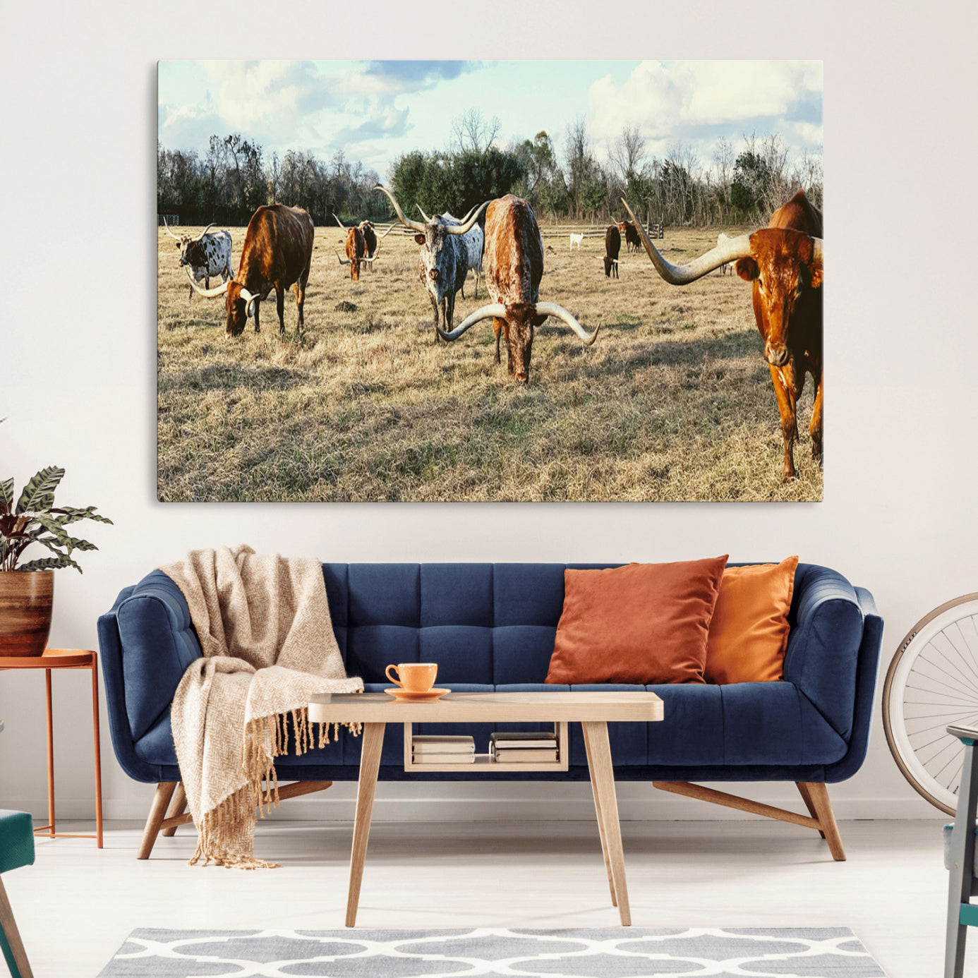 A herd of Texas Longhorn cattle grazing in an open field under a partly cloudy sky, capturing a rustic and Western ranch aesthetic.