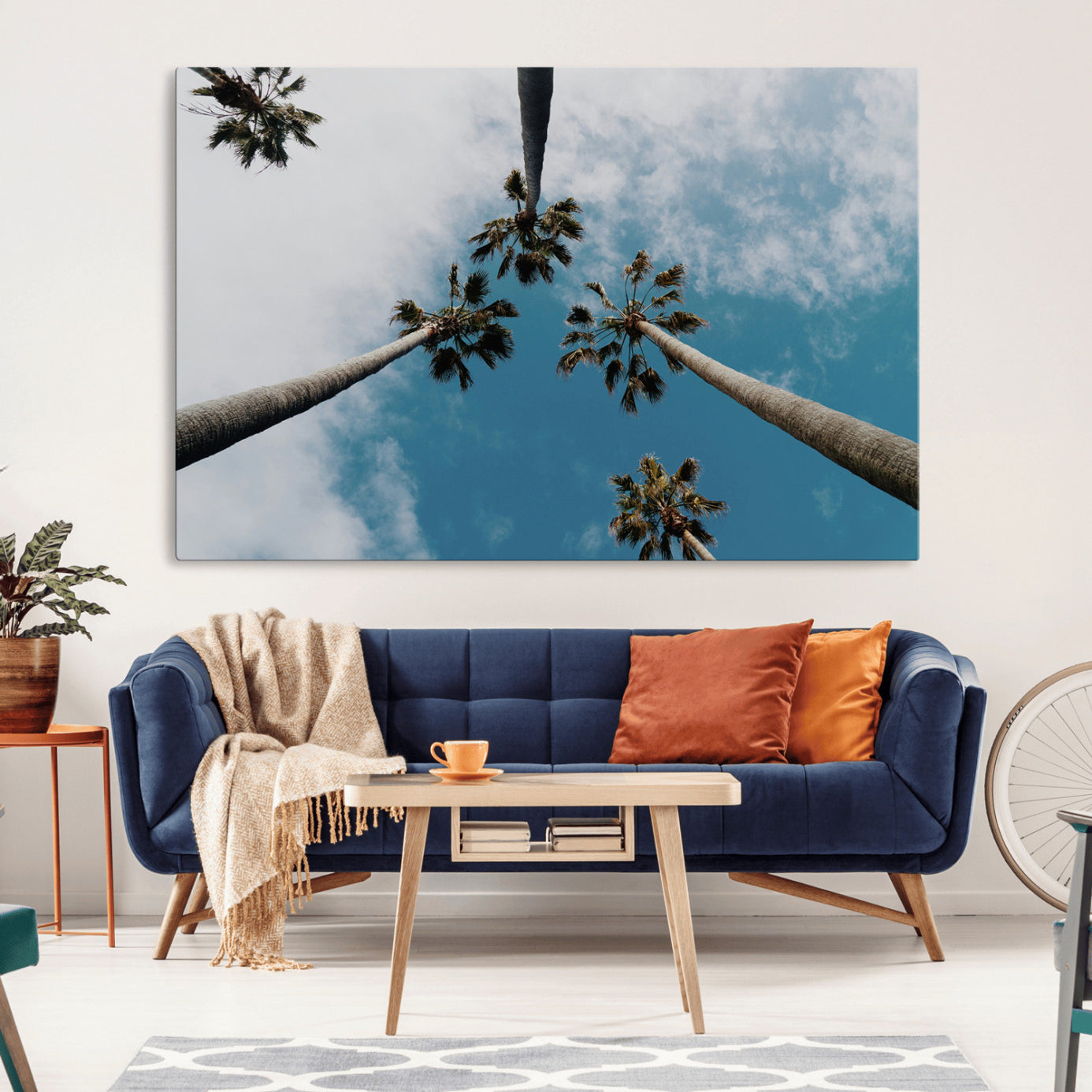 Looking up at tall palm trees against a bright blue sky with scattered clouds, creating a tropical and airy atmosphere for modern home decor.
