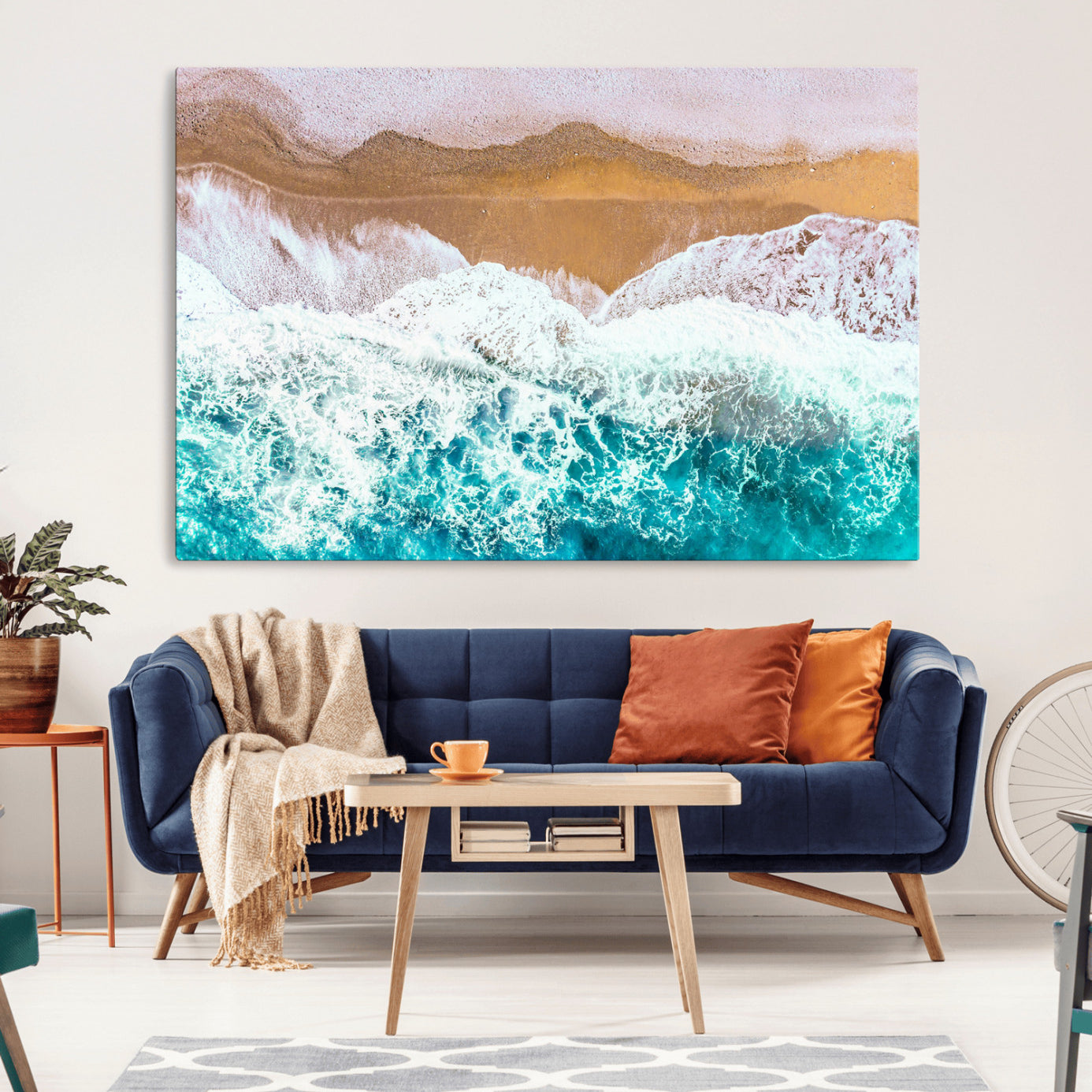 Aerial view of ocean waves crashing onto a sandy beach, with turquoise water and foamy white surf, creating a serene coastal aesthetic for home decor.