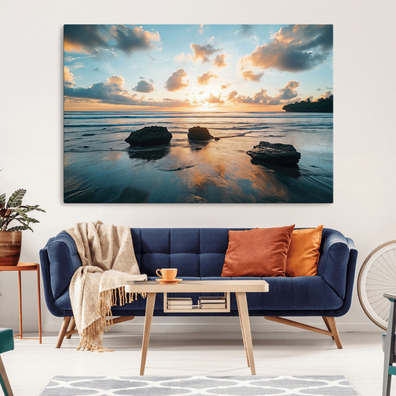 A serene beach at sunset with vibrant clouds, calm water, and rocks in the foreground reflecting the warm colors of the setting sun.