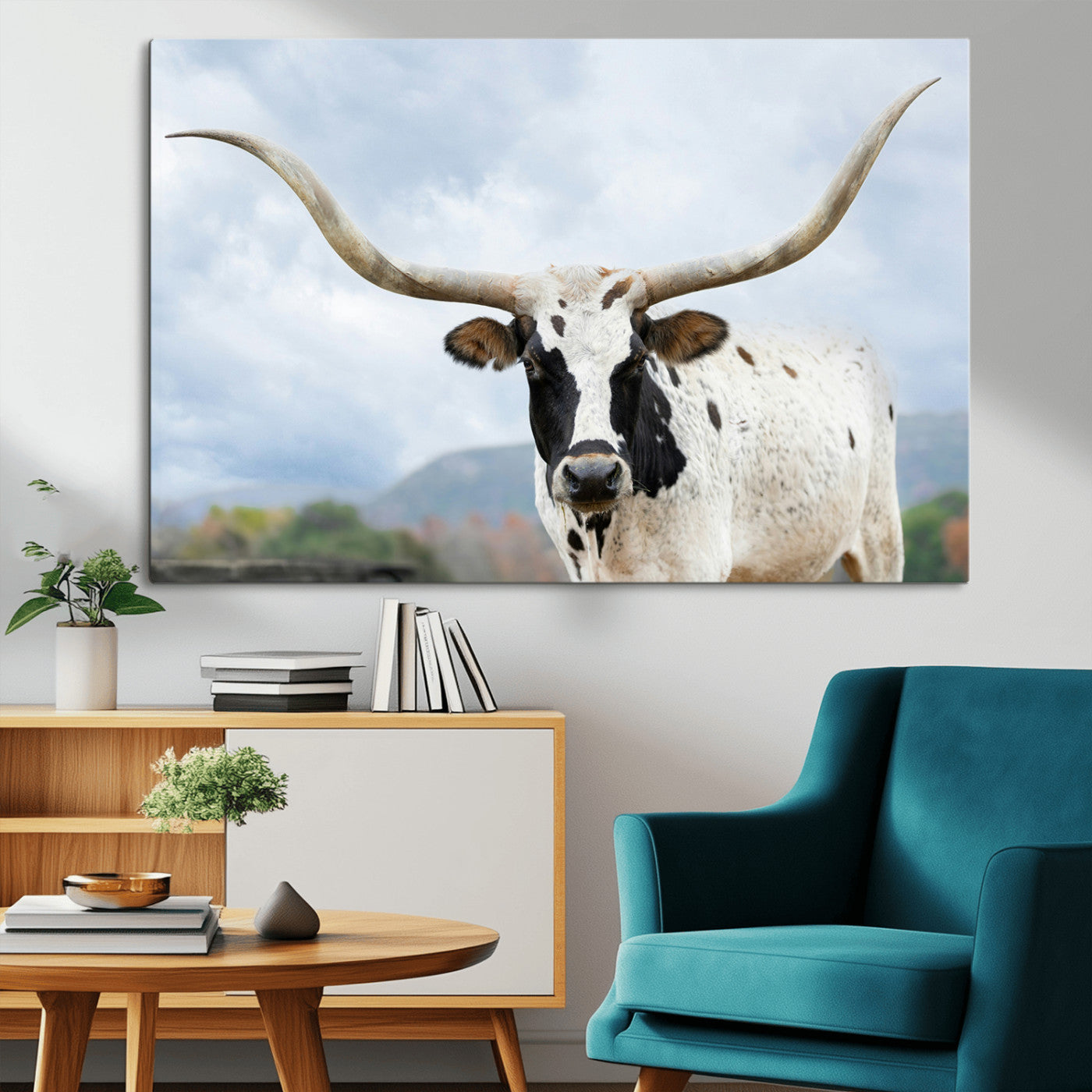 Close-up of a Texas Longhorn with curved horns, black and white markings, set against a cloudy sky and distant hills, perfect for rustic decor.