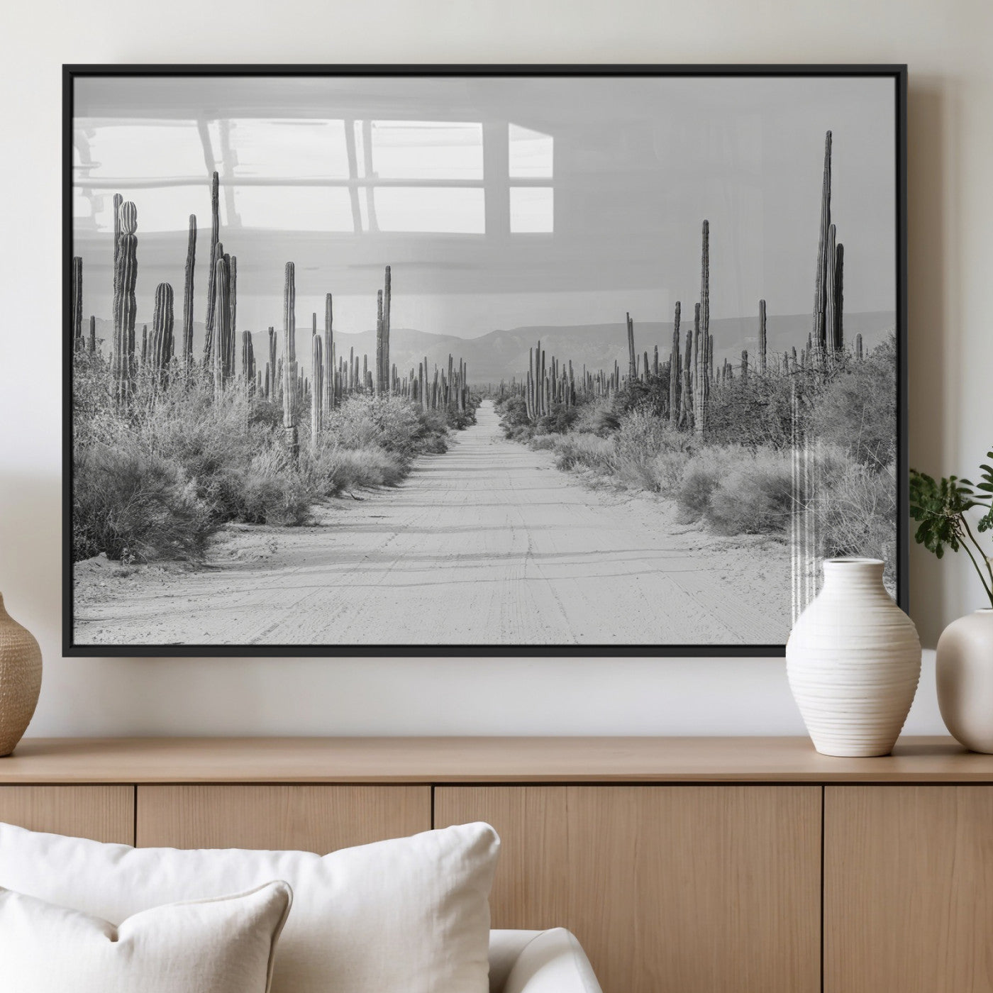 A black and white desert road stretching through a cactus-filled landscape, creating a rugged and timeless southwestern aesthetic with a sense of adventure.