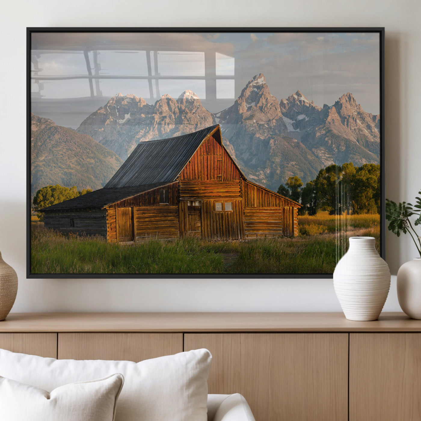 Rustic wooden barn set against towering mountain peaks under warm golden light, creating a peaceful Western countryside scene.