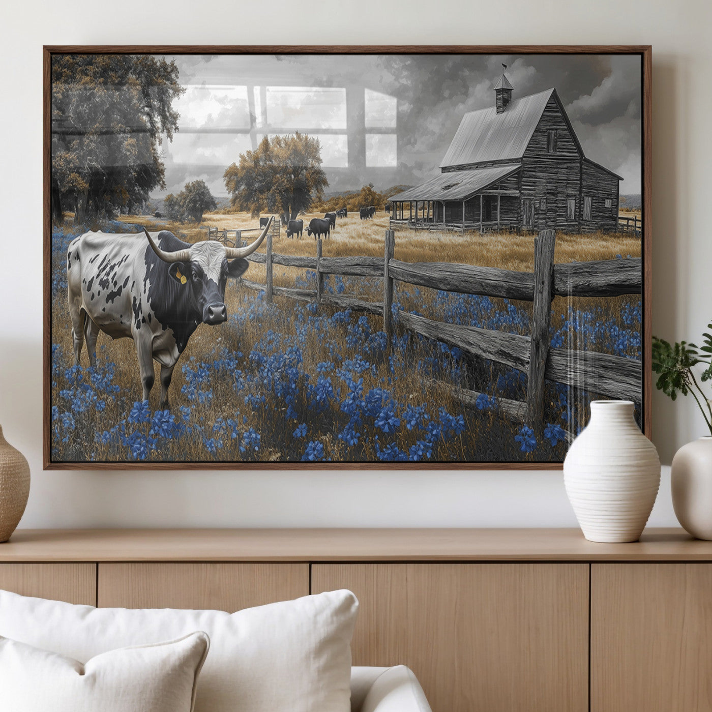 A Texas longhorn stands in front of a rustic barn and wooden fence, with bluebonnets and grazing cattle under dramatic skies.