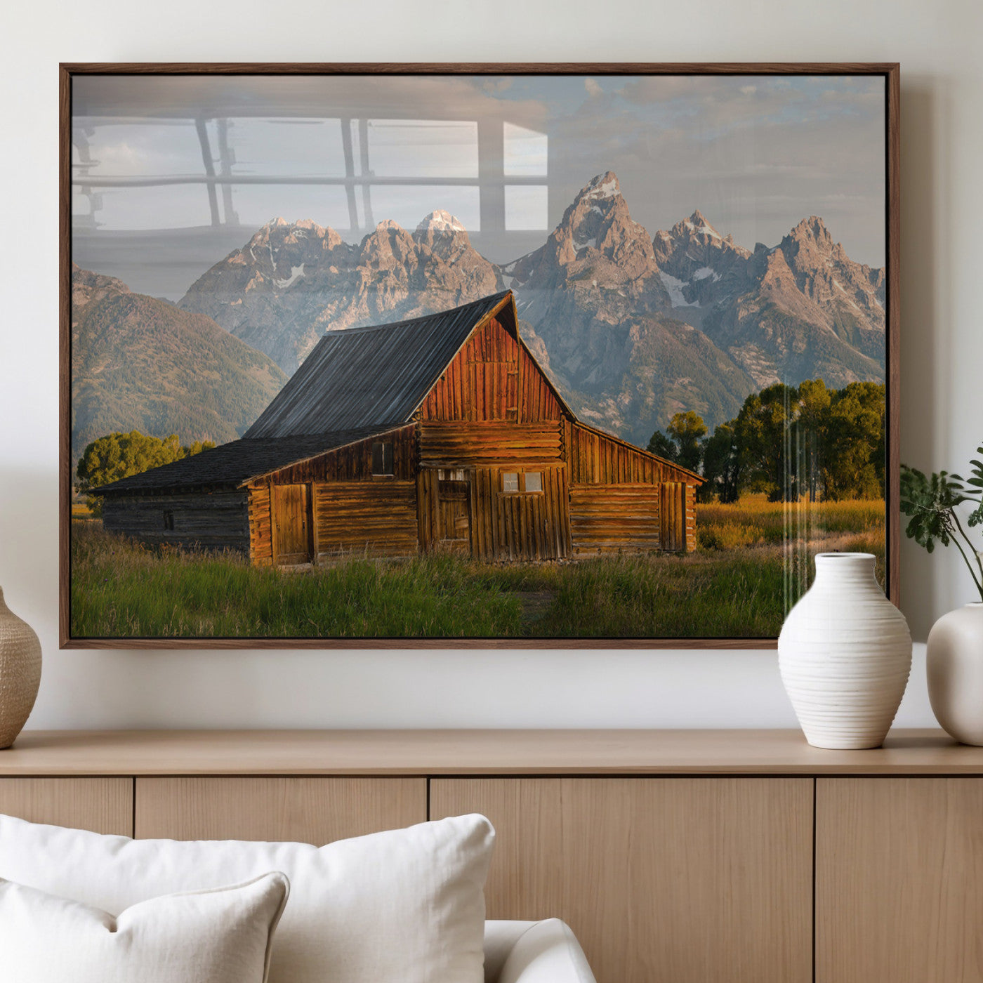 Rustic wooden barn set against towering mountain peaks under warm golden light, creating a peaceful Western countryside scene.