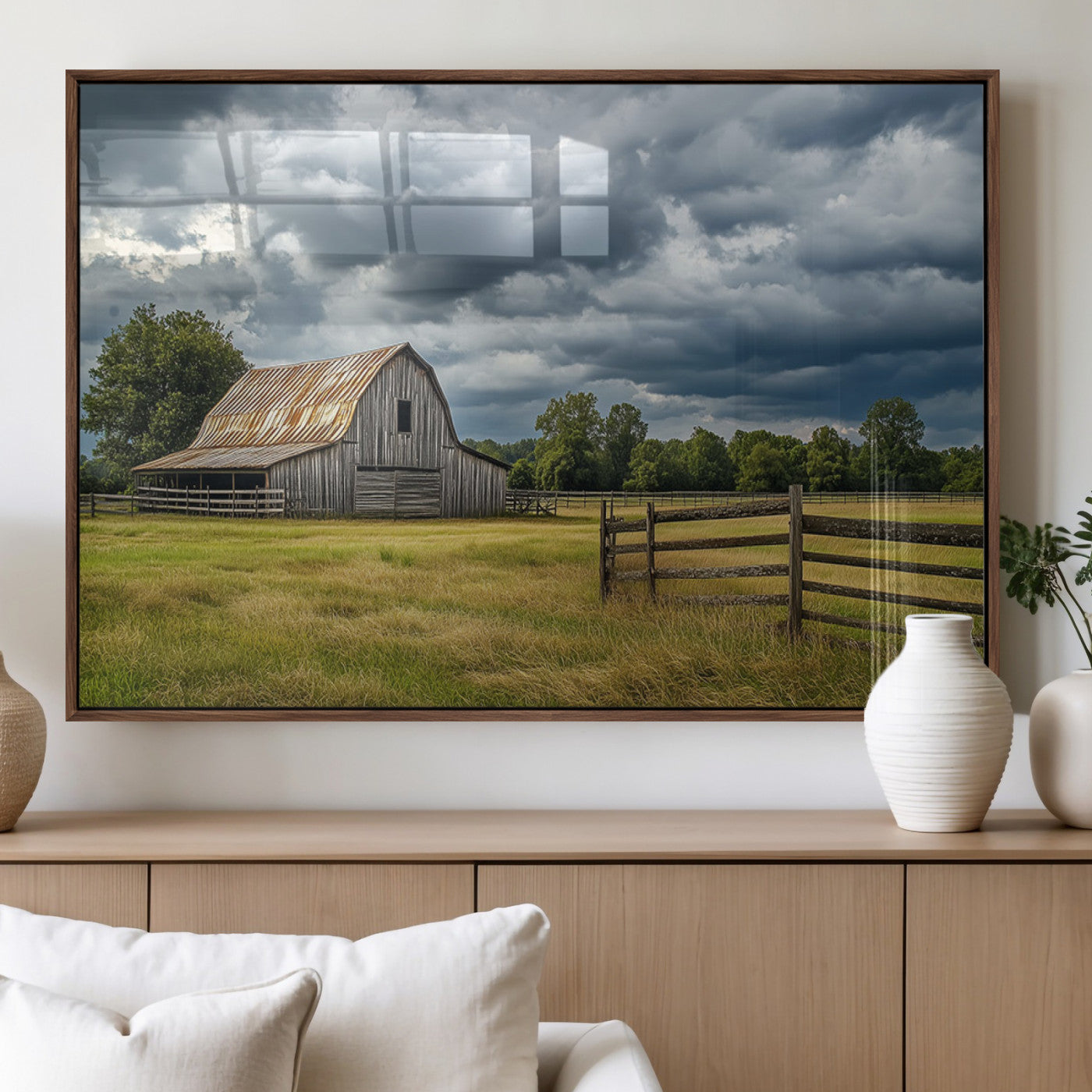 "Rustic barn in a wide open field under a dramatic sky with dark clouds, surrounded by a wooden fence and lush green trees."