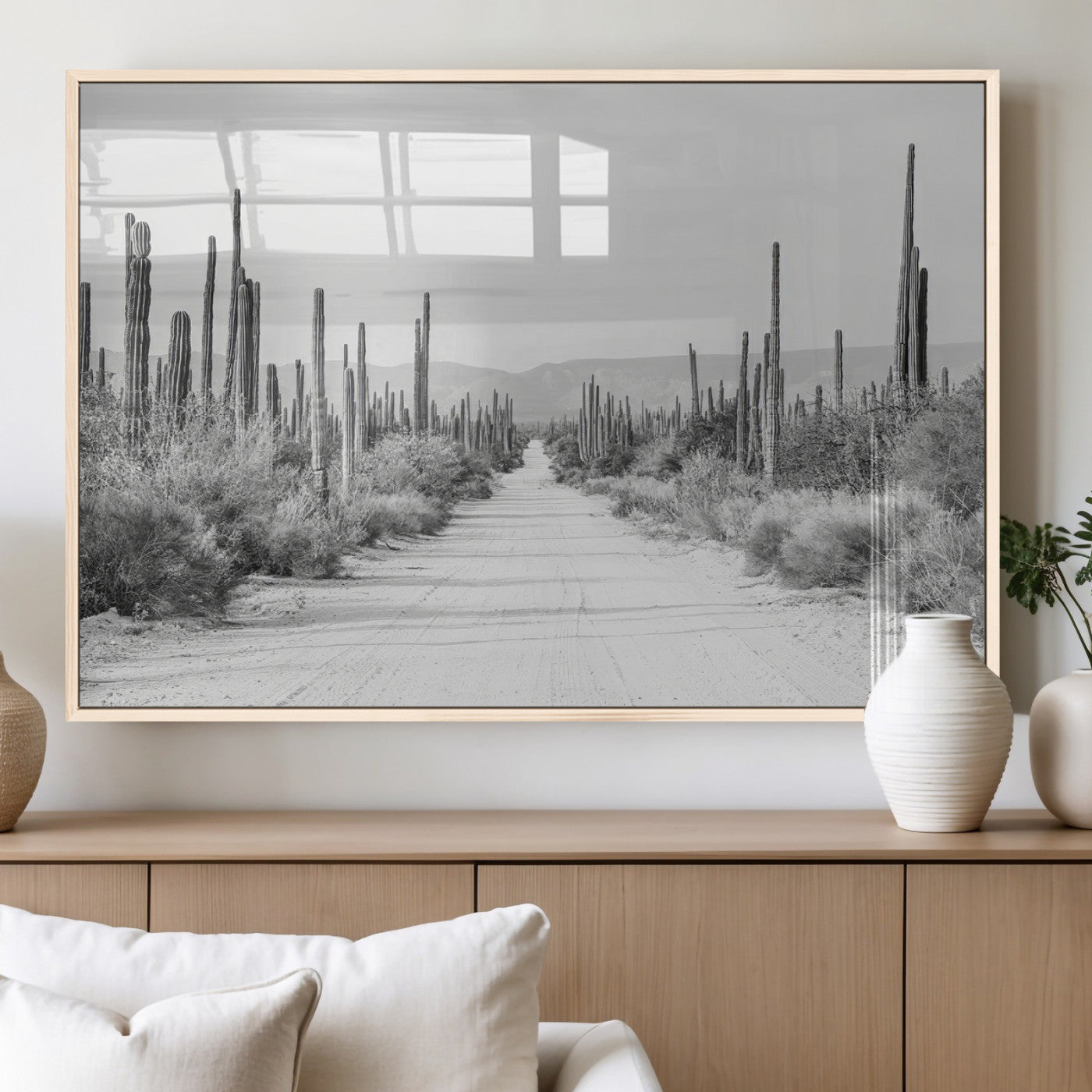 A black and white desert road stretching through a cactus-filled landscape, creating a rugged and timeless southwestern aesthetic with a sense of adventure.