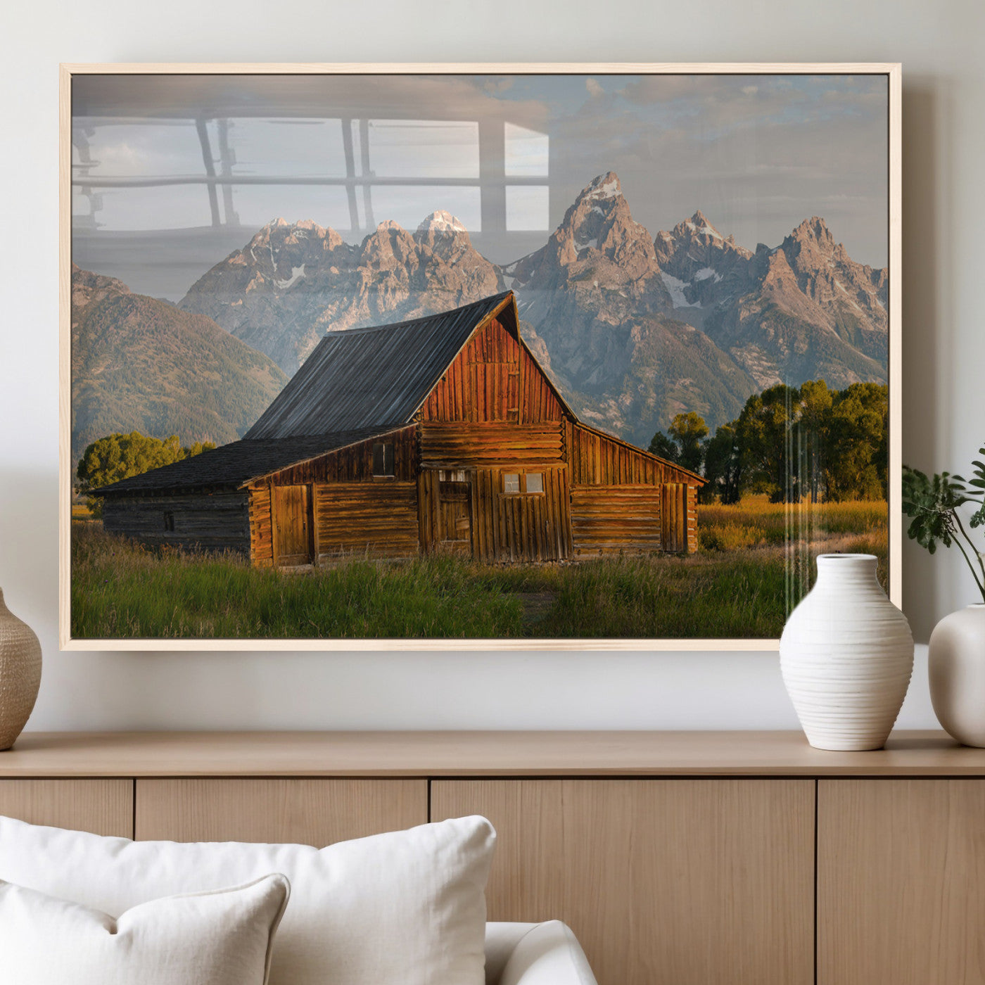 Rustic wooden barn set against towering mountain peaks under warm golden light, creating a peaceful Western countryside scene.