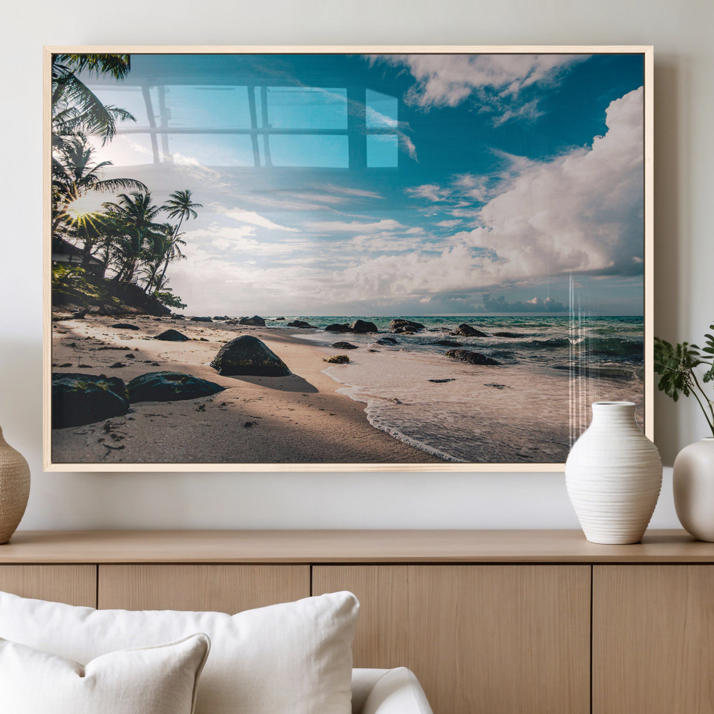 Scenic tropical beach with palm trees, ocean waves, and rocky shoreline under a bright blue sky, creating a serene coastal vibe.