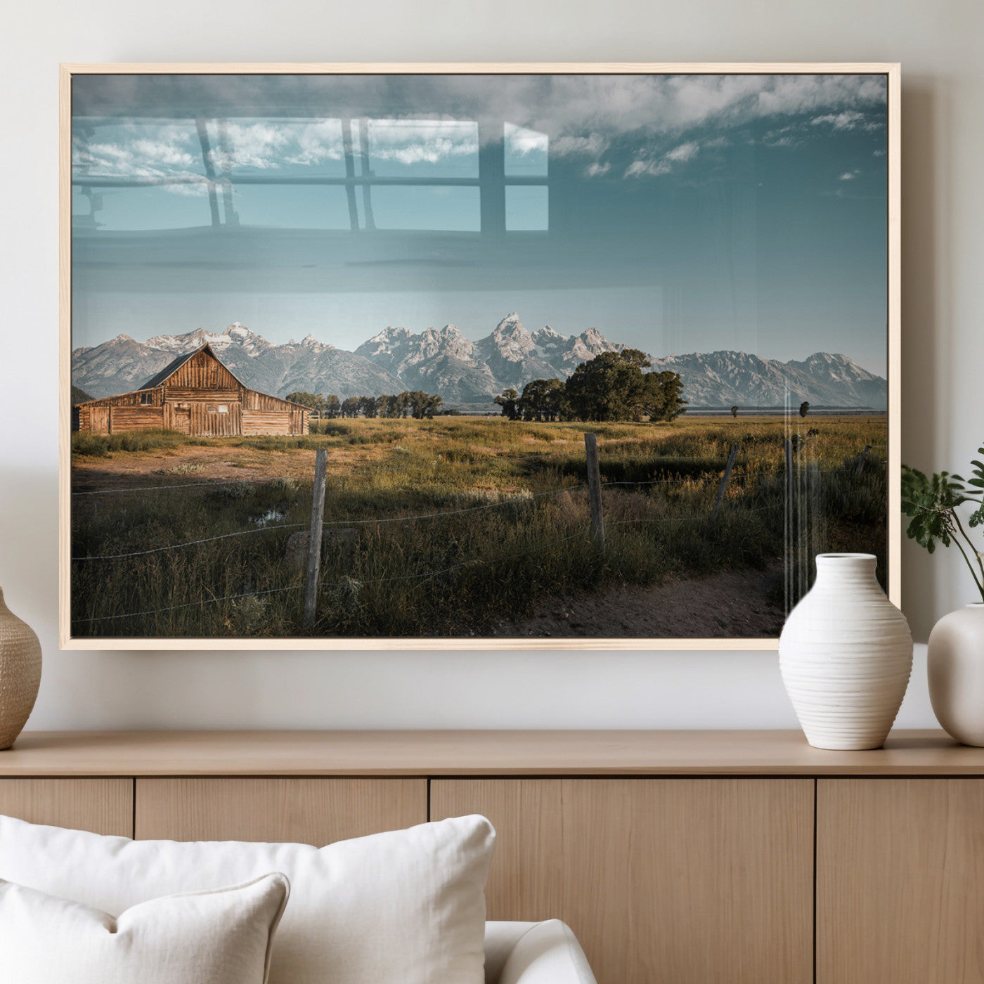 A rustic farmhouse with a wooden barn set against majestic mountain peaks under a soft blue sky, evoking peaceful countryside charm.