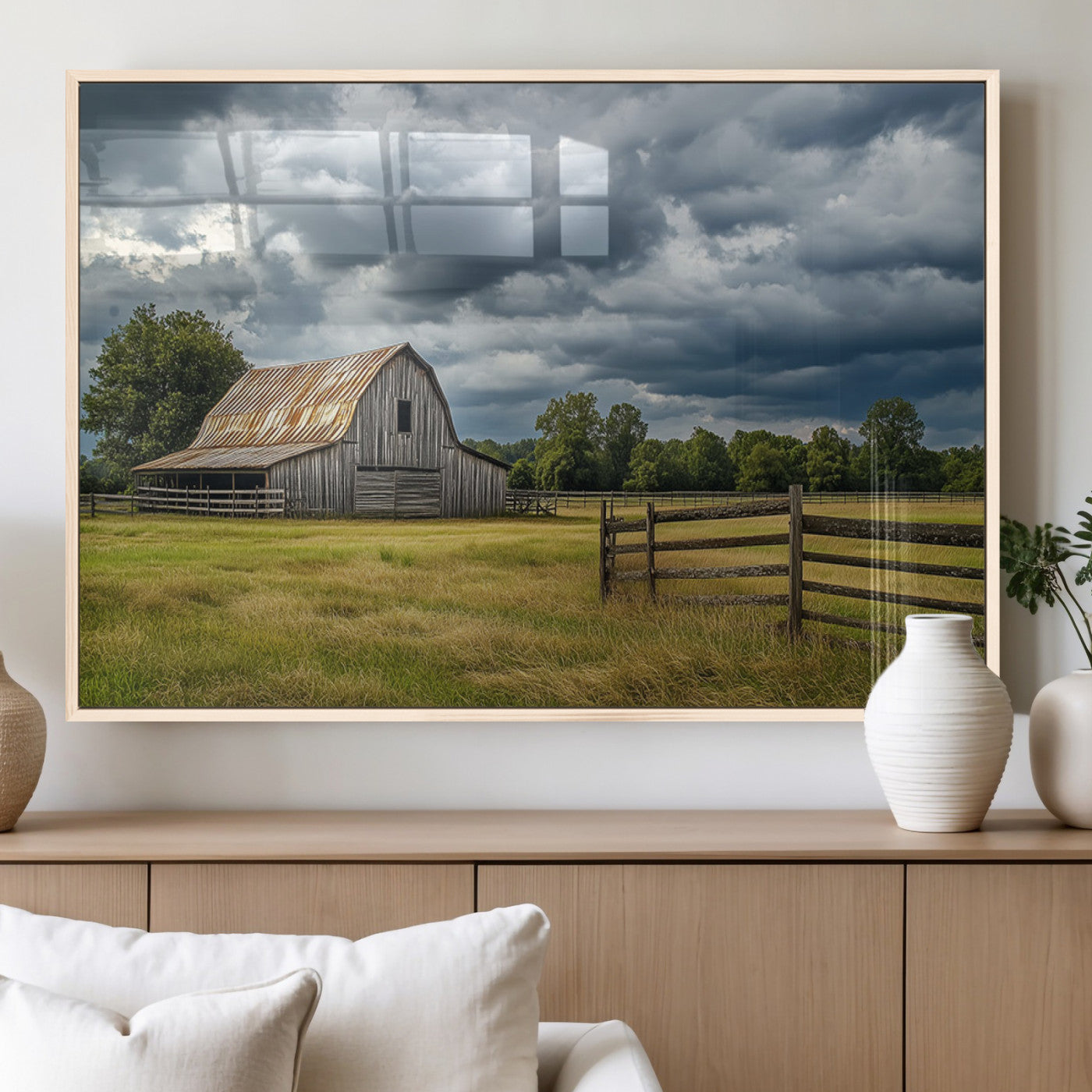 "Rustic barn in a wide open field under a dramatic sky with dark clouds, surrounded by a wooden fence and lush green trees."