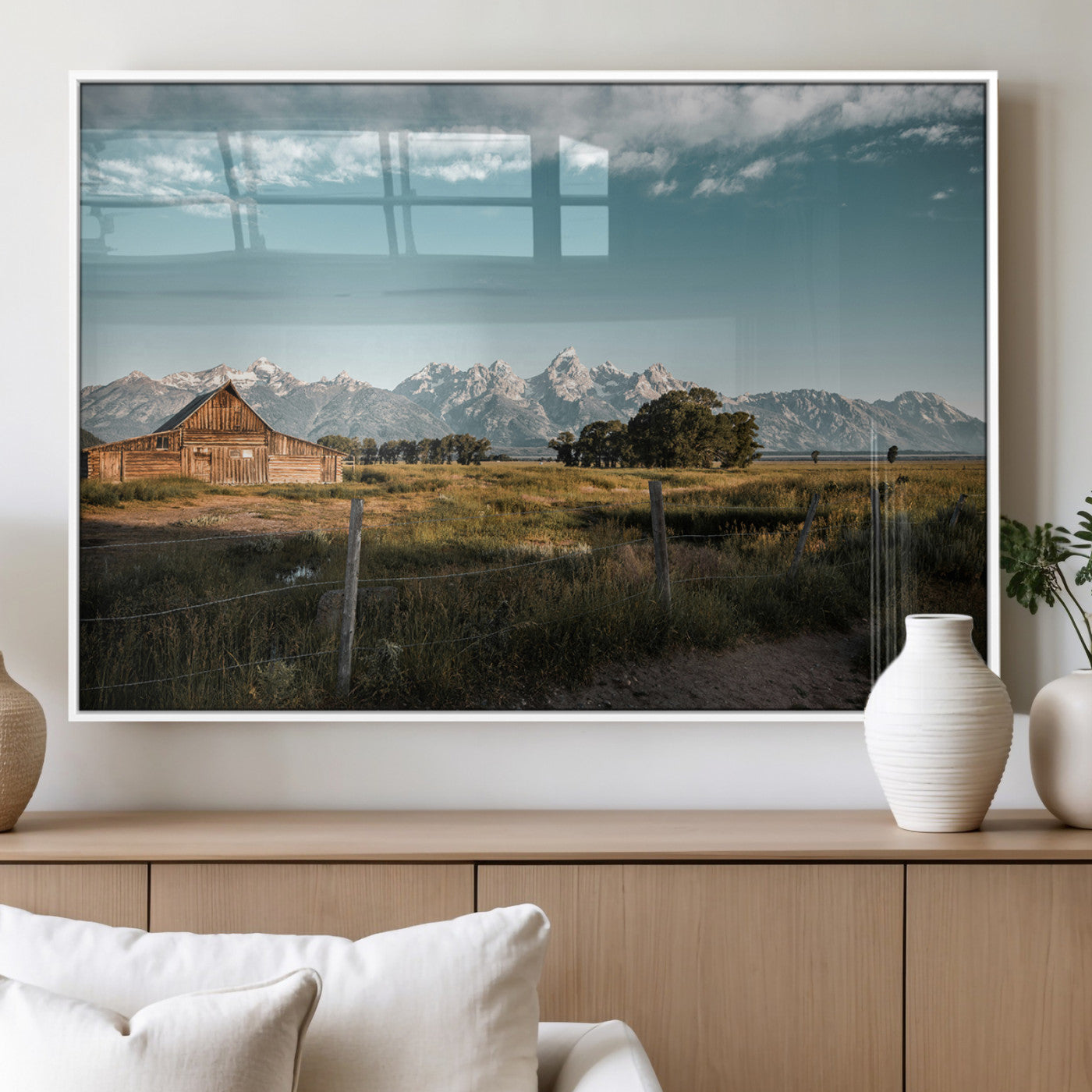 A rustic farmhouse with a wooden barn set against majestic mountain peaks under a soft blue sky, evoking peaceful countryside charm.