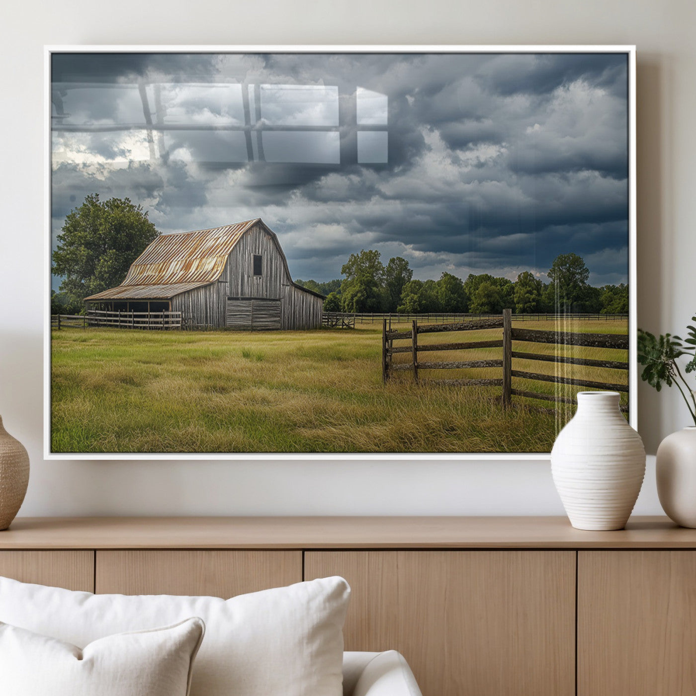 "Rustic barn in a wide open field under a dramatic sky with dark clouds, surrounded by a wooden fence and lush green trees."