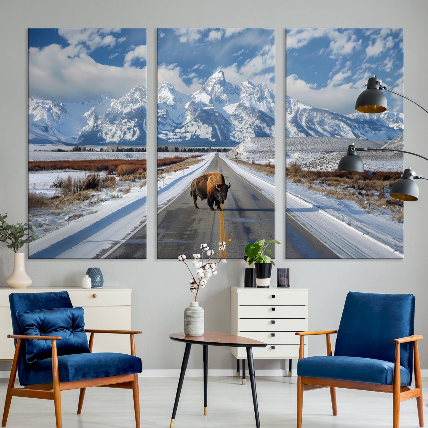 A powerful bison stands on a snow-dusted road beneath the towering peaks of the Grand Tetons, capturing the untamed beauty of America's winter wilderness.