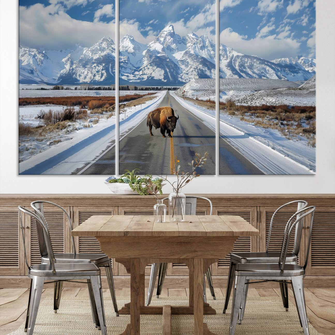 A powerful bison stands on a snow-dusted road beneath the towering peaks of the Grand Tetons, capturing the untamed beauty of America's winter wilderness.
