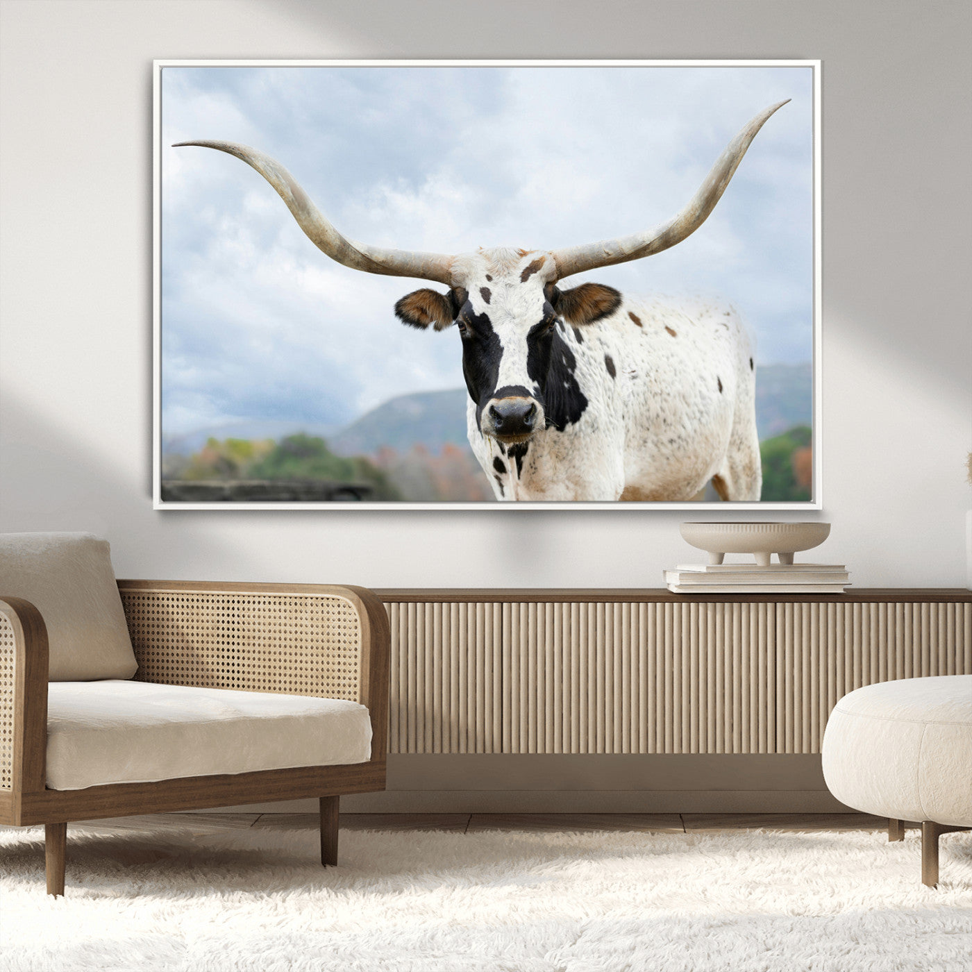 Close-up of a Texas Longhorn with curved horns, black and white markings, set against a cloudy sky and distant hills, perfect for rustic decor.