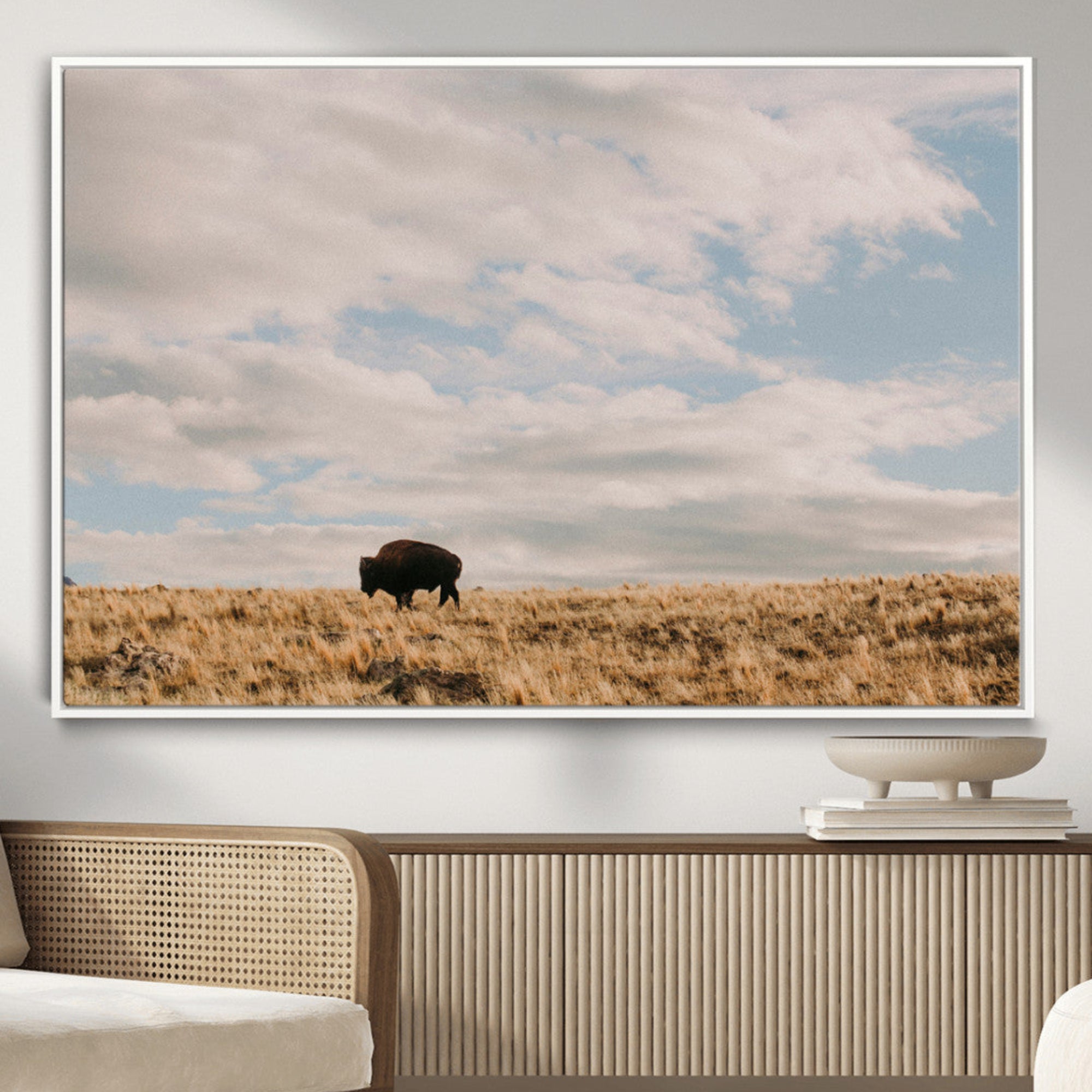 A solitary bison walking across a golden prairie under a vast, cloud-filled sky, evoking a peaceful, rustic western landscape for home decor.