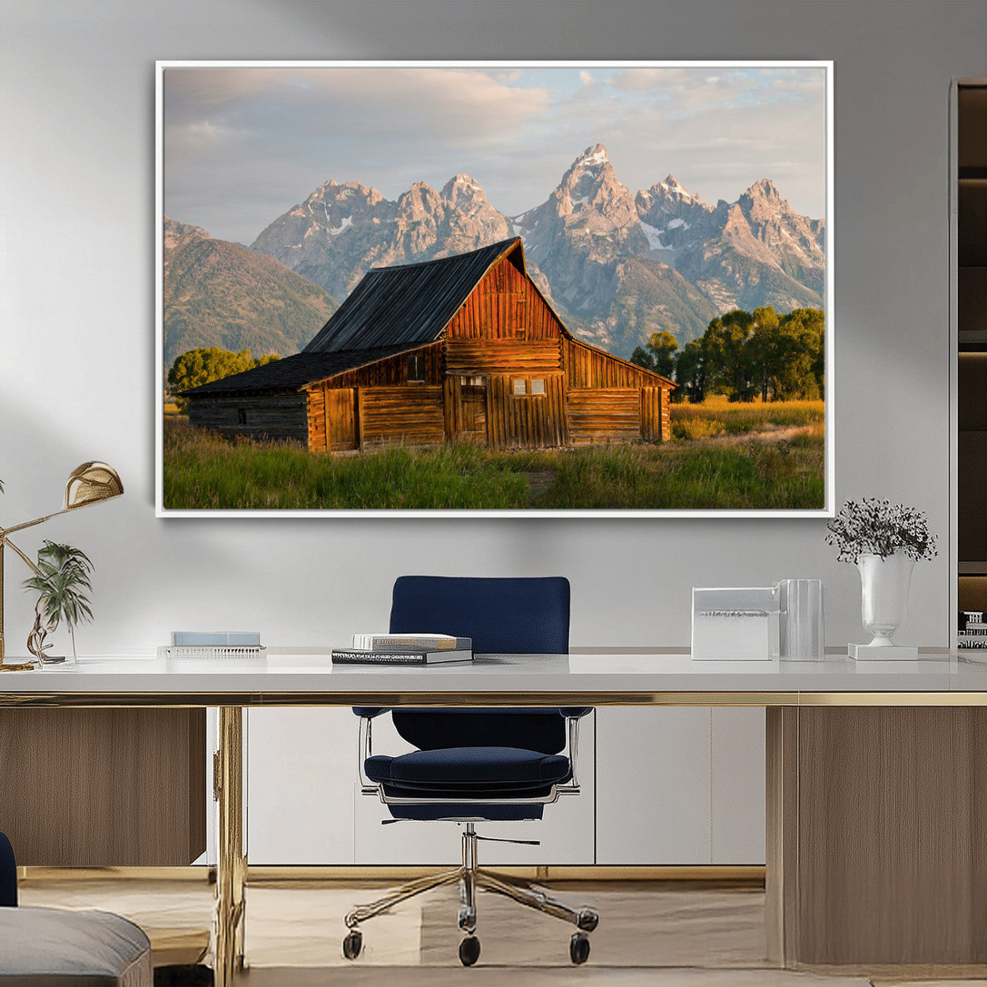 Rustic wooden barn set against towering mountain peaks under warm golden light, creating a peaceful Western countryside scene.