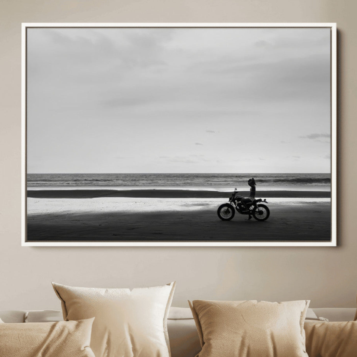 A motorcyclist on a vast beach, gazing at the ocean, capturing a moody and tranquil coastal adventure in black and white.
