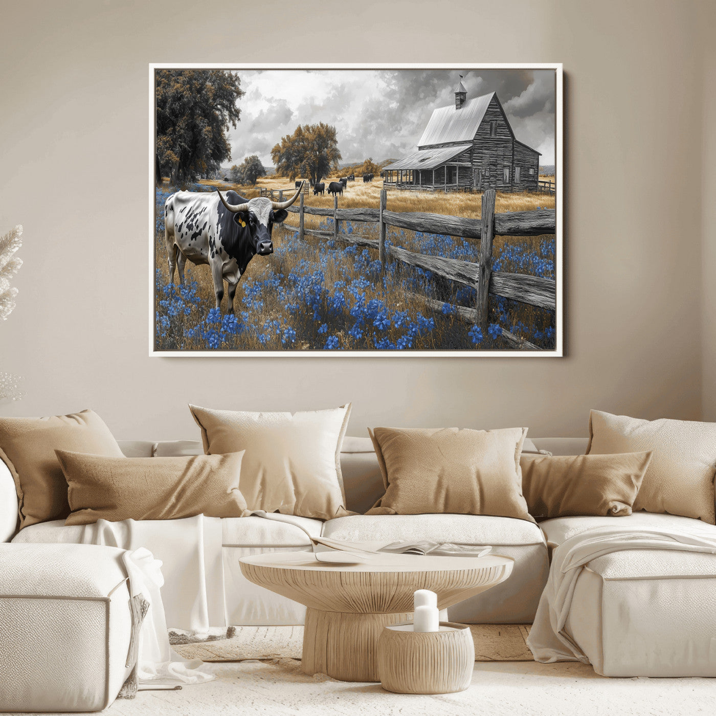 A Texas longhorn stands in front of a rustic barn and wooden fence, with bluebonnets and grazing cattle under dramatic skies.