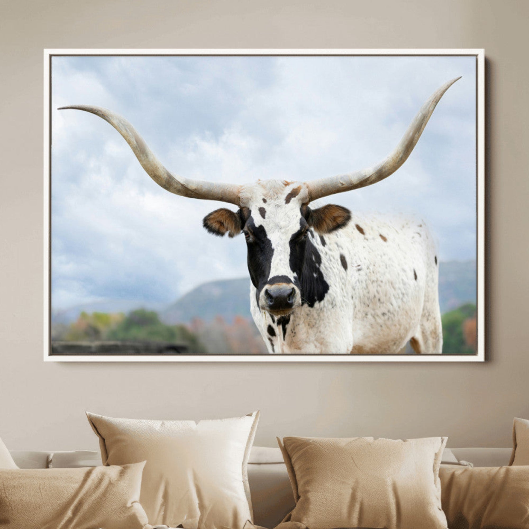 Close-up of a Texas Longhorn with curved horns, black and white markings, set against a cloudy sky and distant hills, perfect for rustic decor.