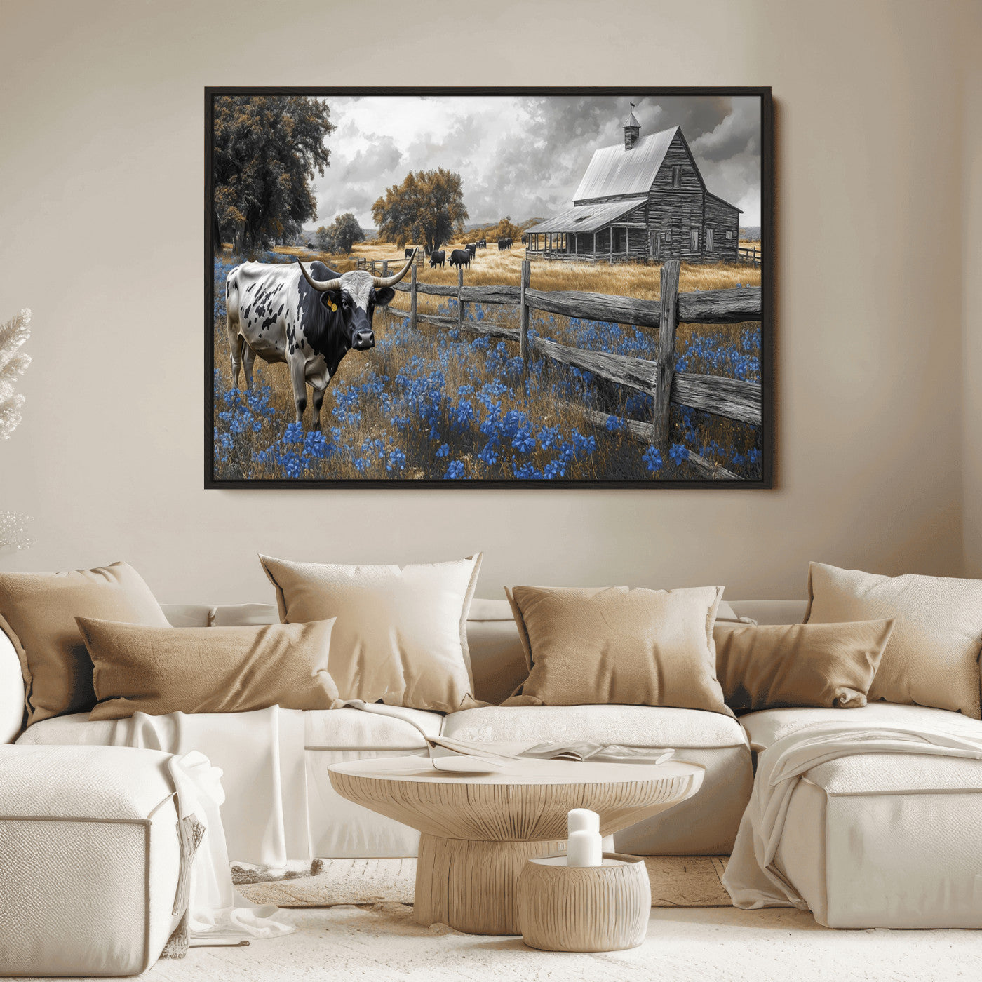 A Texas longhorn stands in front of a rustic barn and wooden fence, with bluebonnets and grazing cattle under dramatic skies.