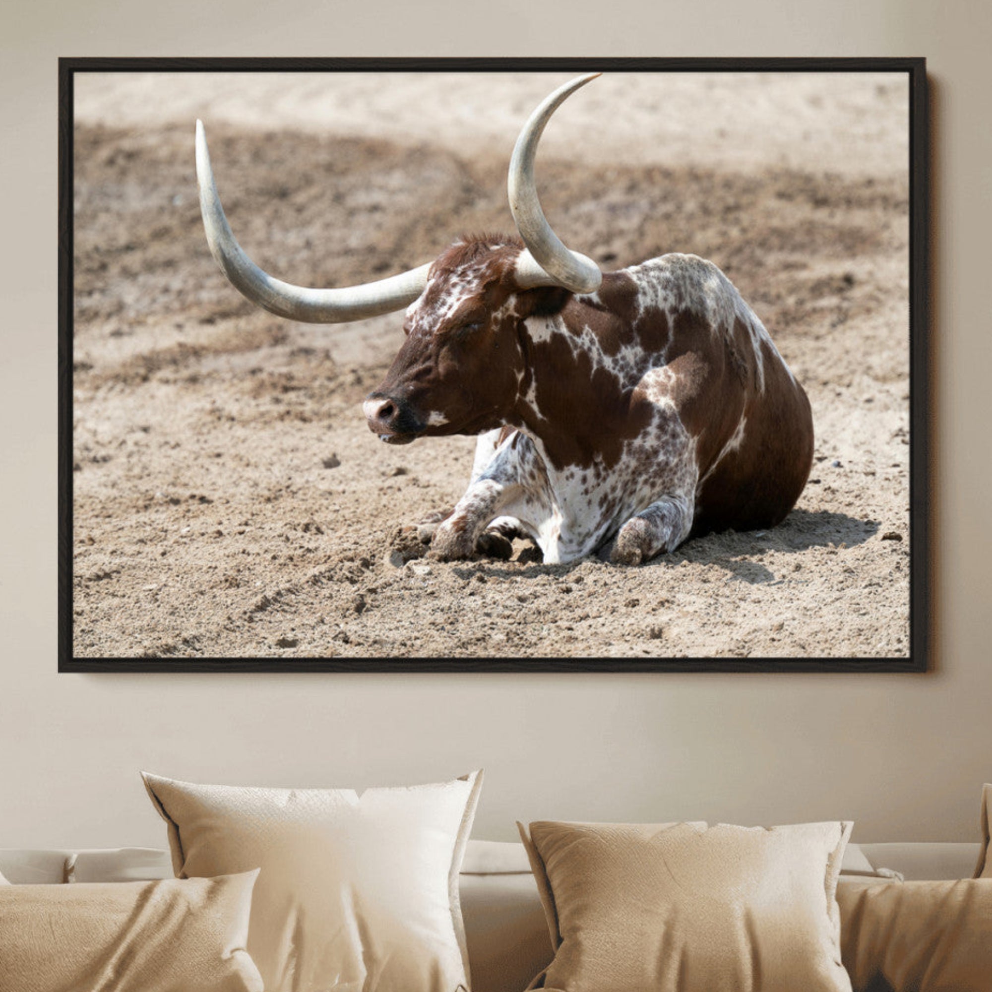 Texas Longhorn resting on sandy ground with large curved horns, capturing a rustic Western aesthetic perfect for farmhouse-style wall art.