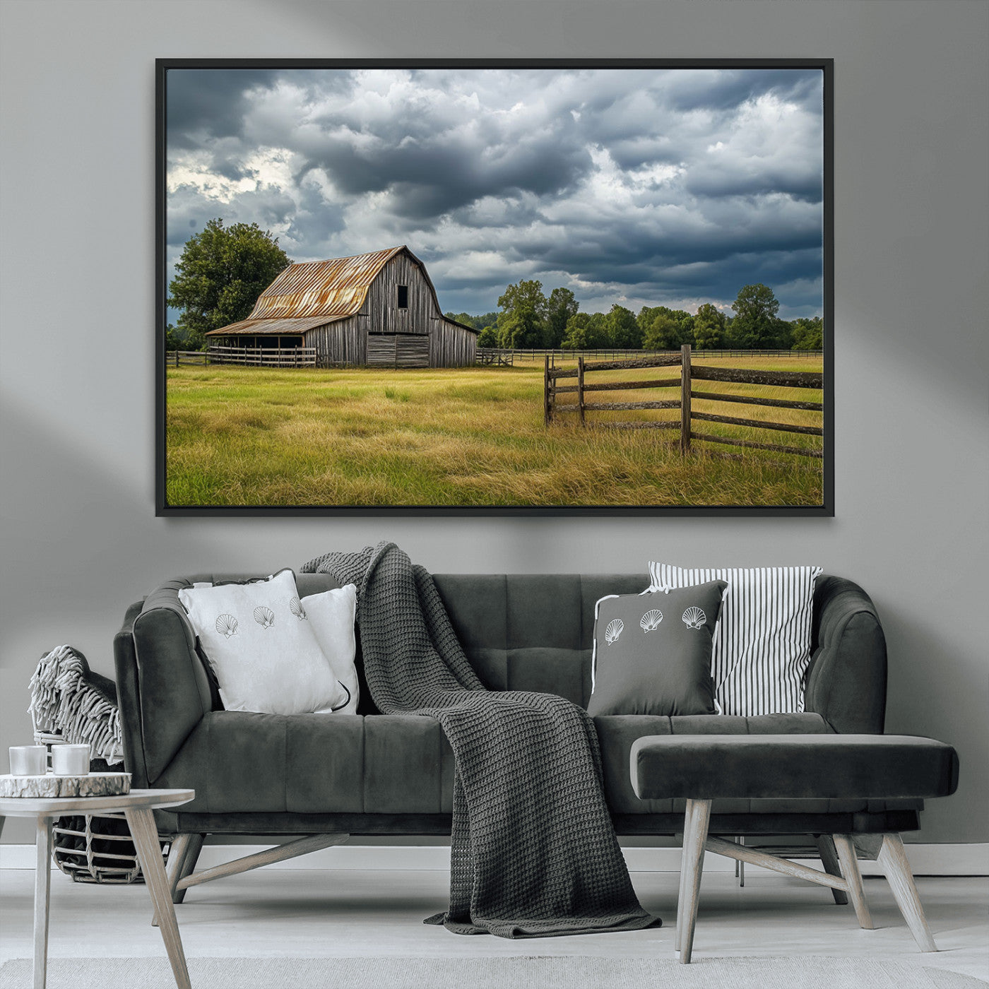 "Rustic barn in a wide open field under a dramatic sky with dark clouds, surrounded by a wooden fence and lush green trees."