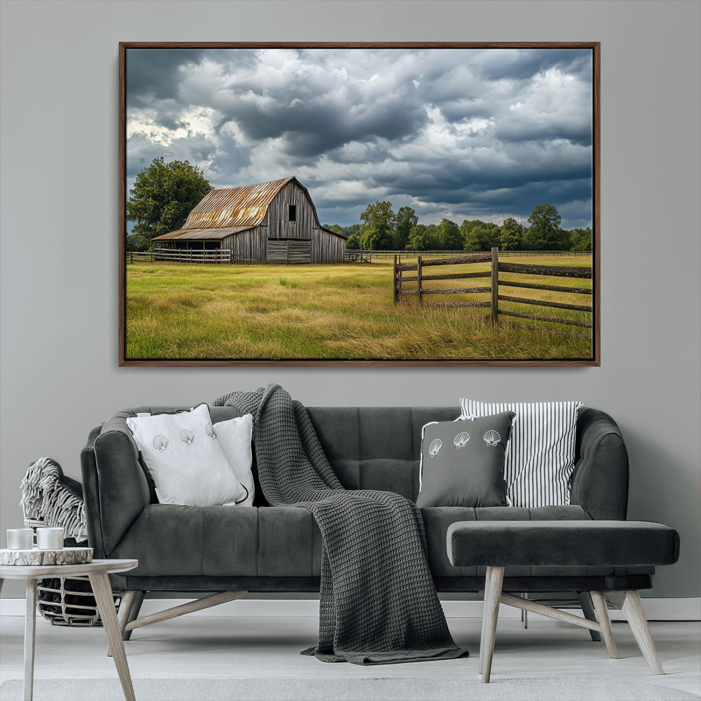 "Rustic barn in a wide open field under a dramatic sky with dark clouds, surrounded by a wooden fence and lush green trees."