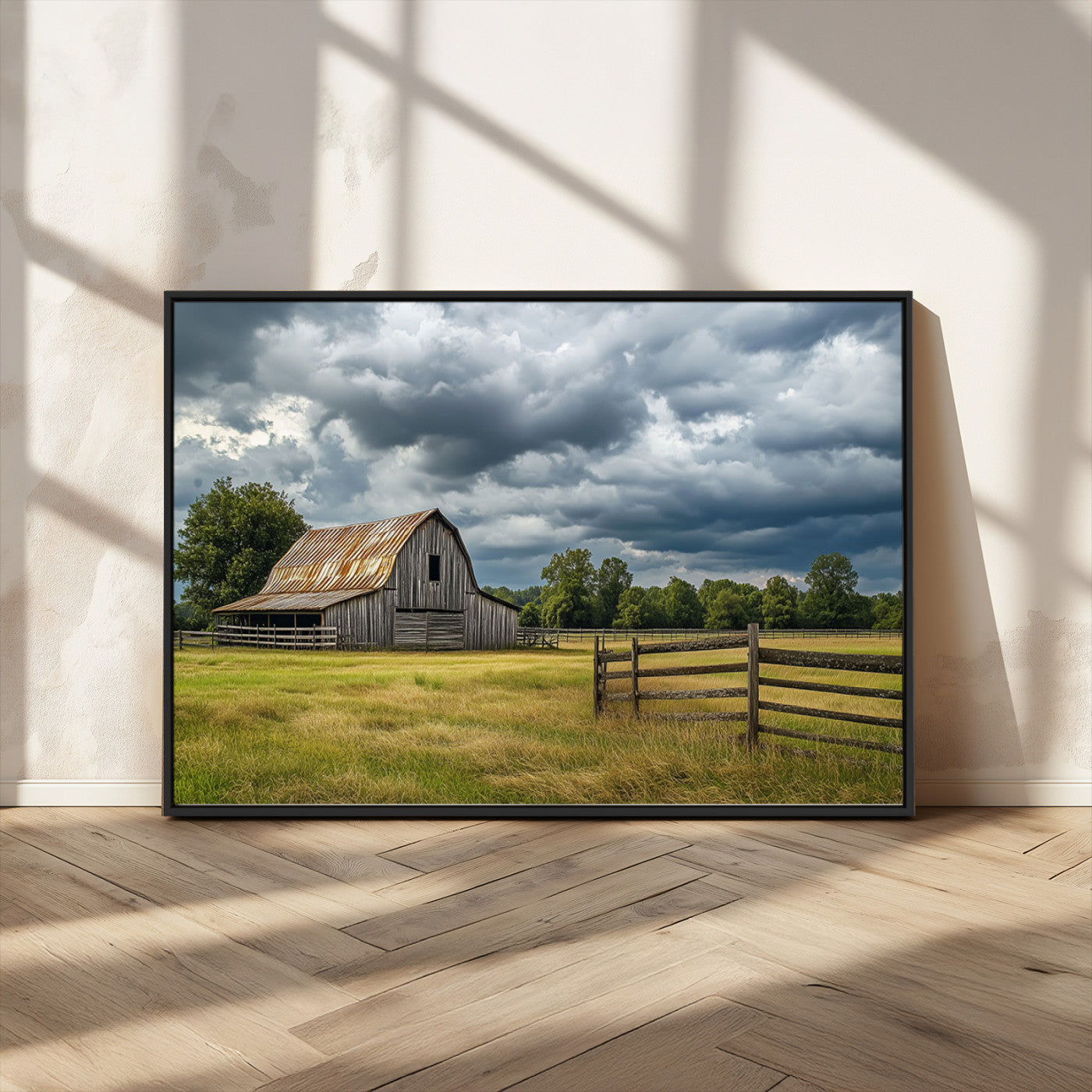 "Rustic barn in a wide open field under a dramatic sky with dark clouds, surrounded by a wooden fence and lush green trees."