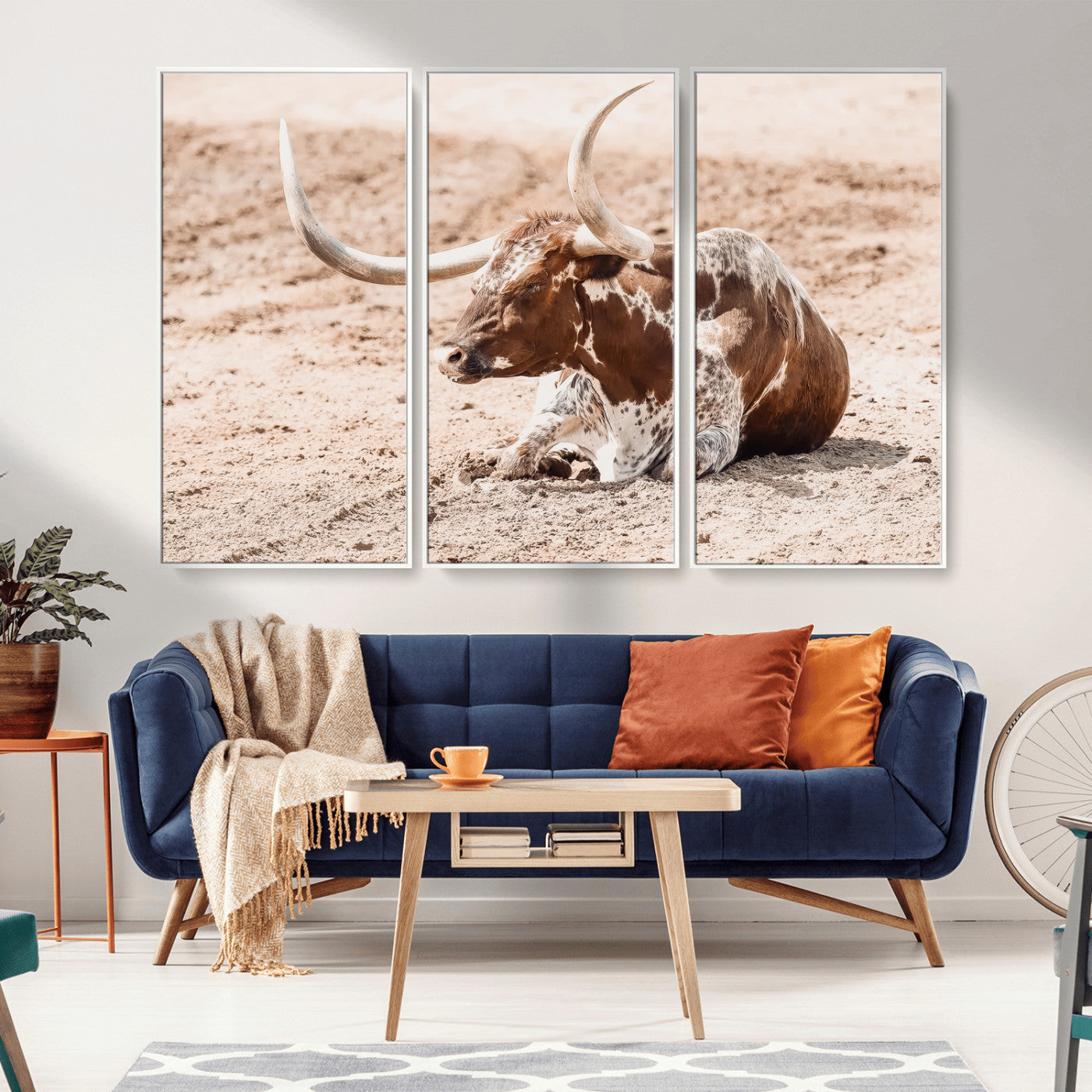 Texas Longhorn bull resting on dusty ground with warm tones, ideal for rustic western or farmhouse-themed wall decor.