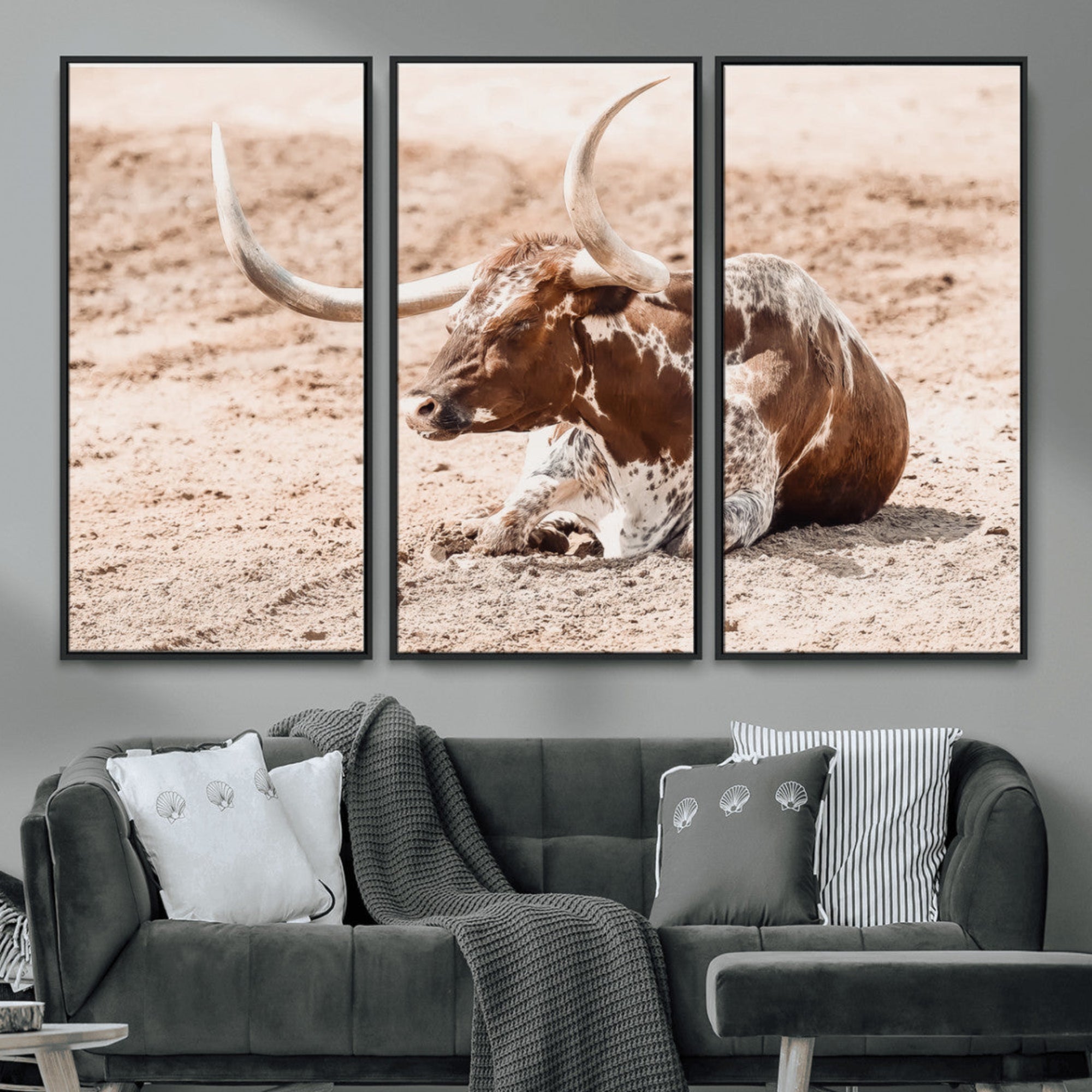 Texas Longhorn bull resting on dusty ground with warm tones, ideal for rustic western or farmhouse-themed wall decor.