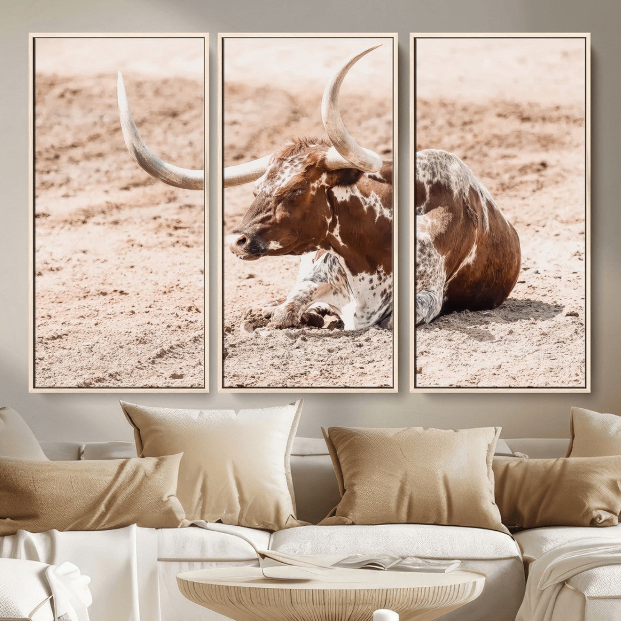 Texas Longhorn bull resting on dusty ground with warm tones, ideal for rustic western or farmhouse-themed wall decor.